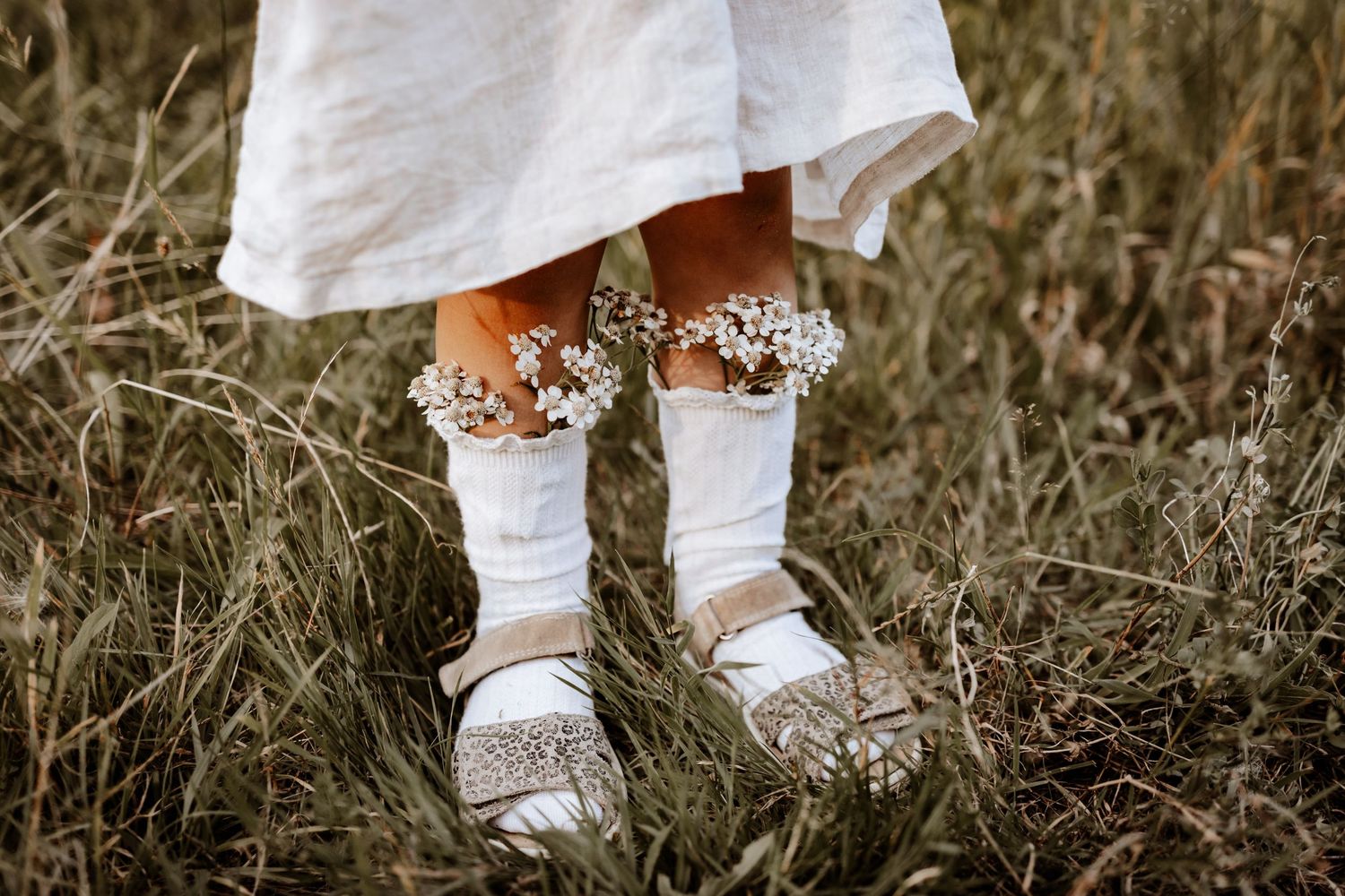 Mädchen mit Sandalen und Kniestrümpfen, worin Blumen stecken