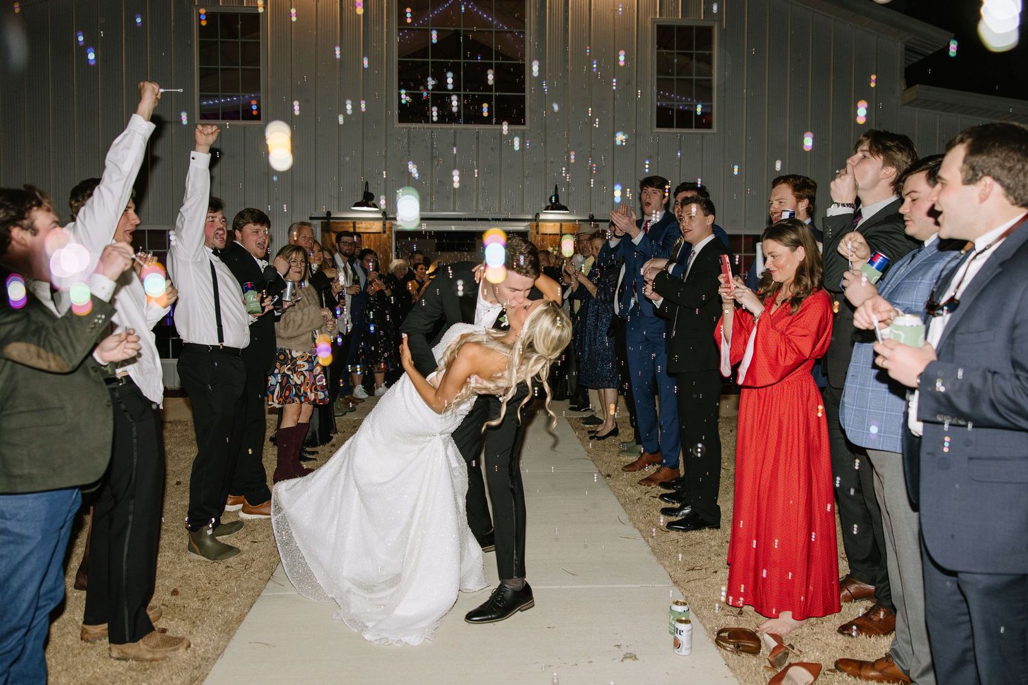 Wedding reception dance floor filled with guests celebrating under dimmed lights.