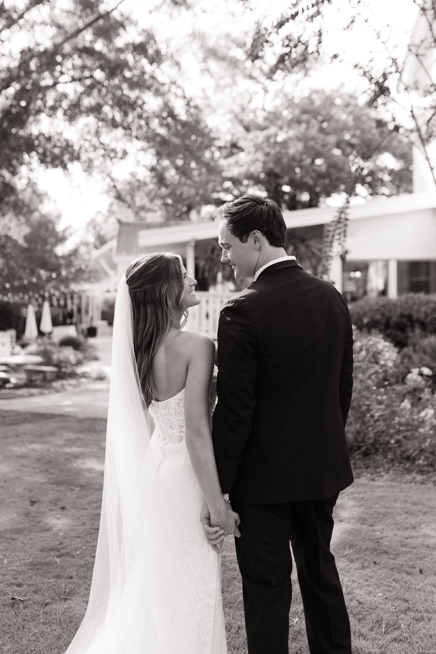 Black and white wedding portrait showing couple walking away on garden path.