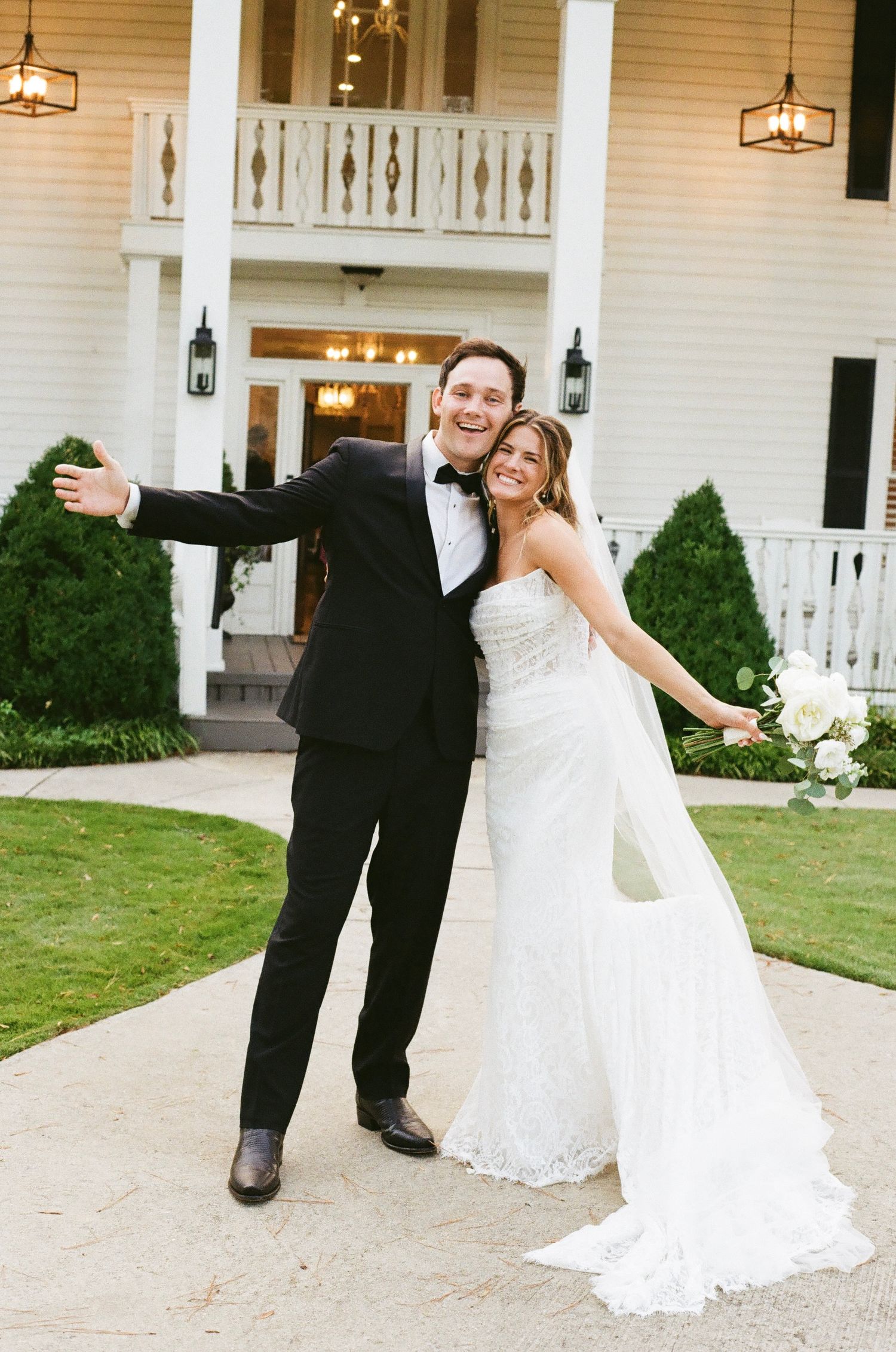 Couple shares romantic dance moves outside white colonial-style wedding venue.