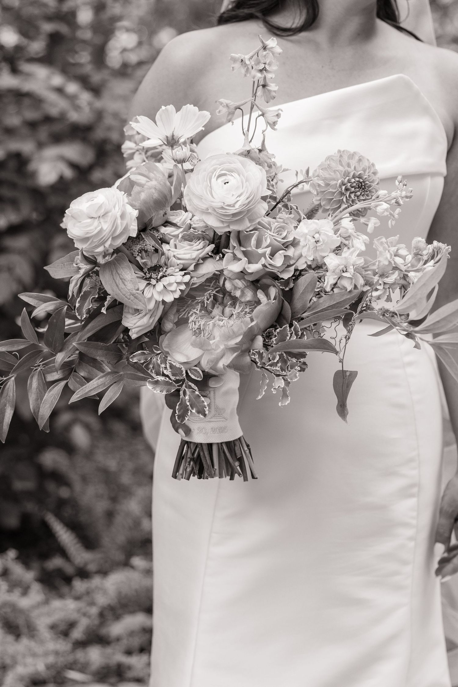 A series of elegant white wedding bouquets with mixed flowers and greenery shown against a white dress in black and white.
