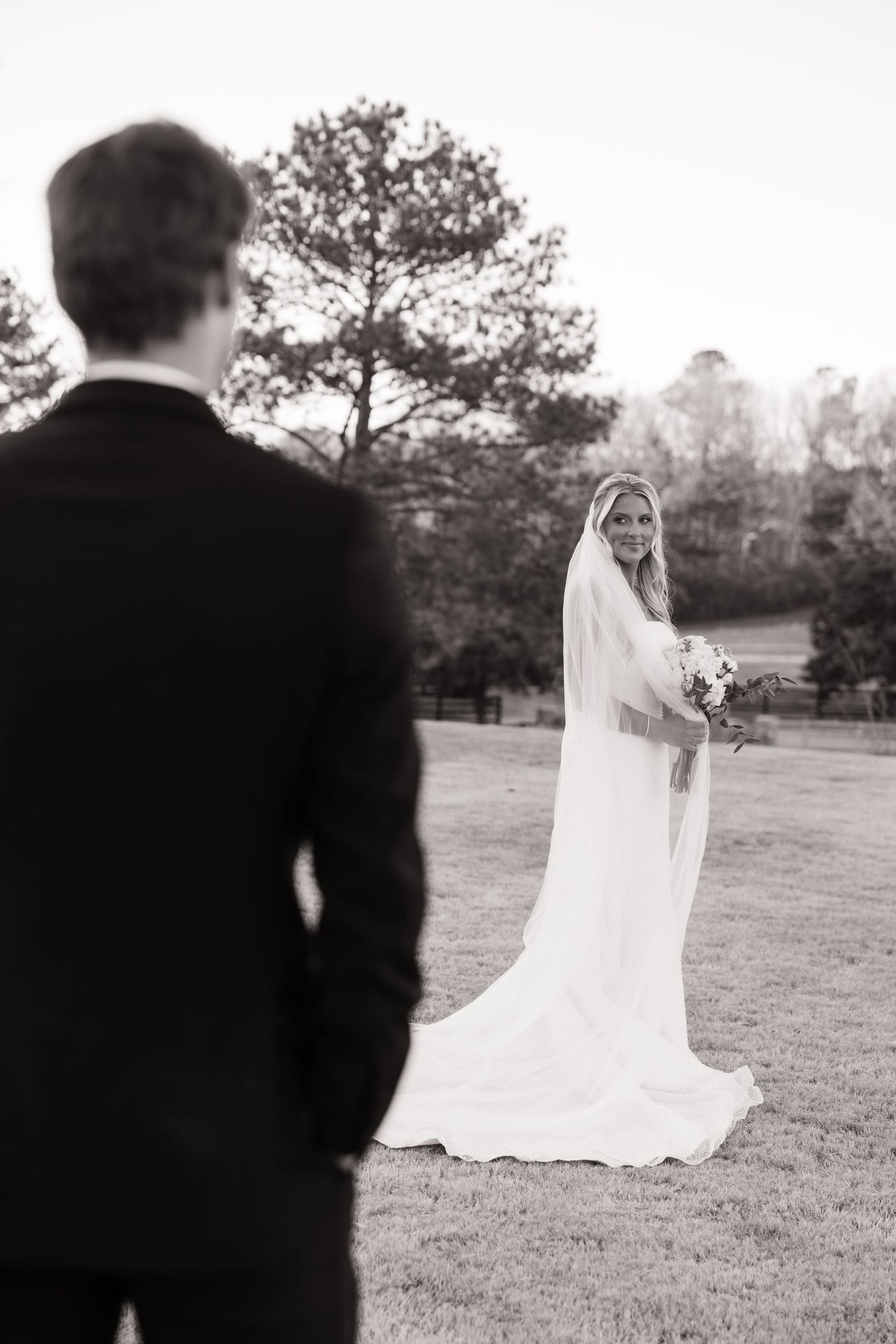 Artistic black and white first look moment between couple on wedding grounds.
