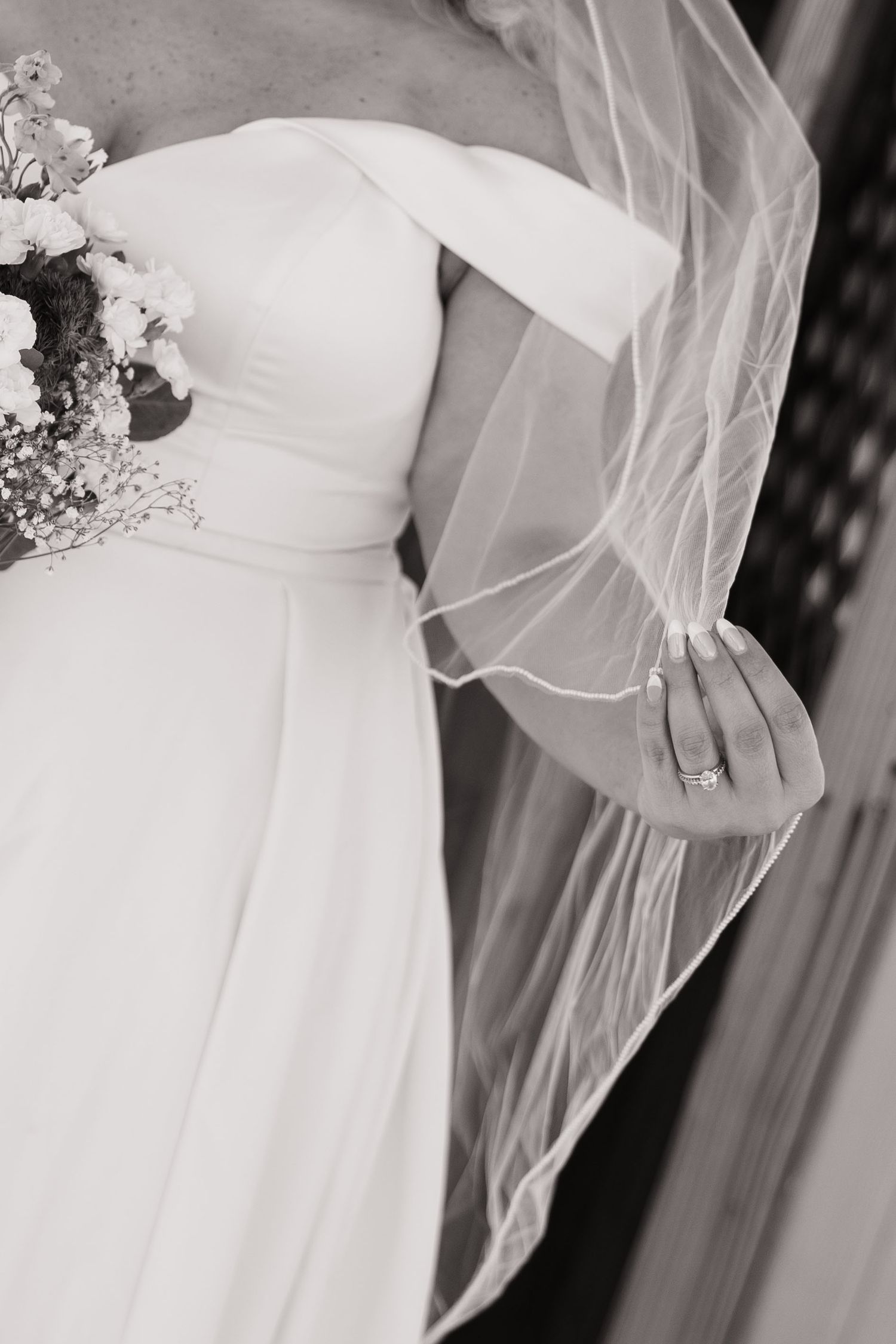 Close-up details of a white wedding dress with delicate veil and lace elements.