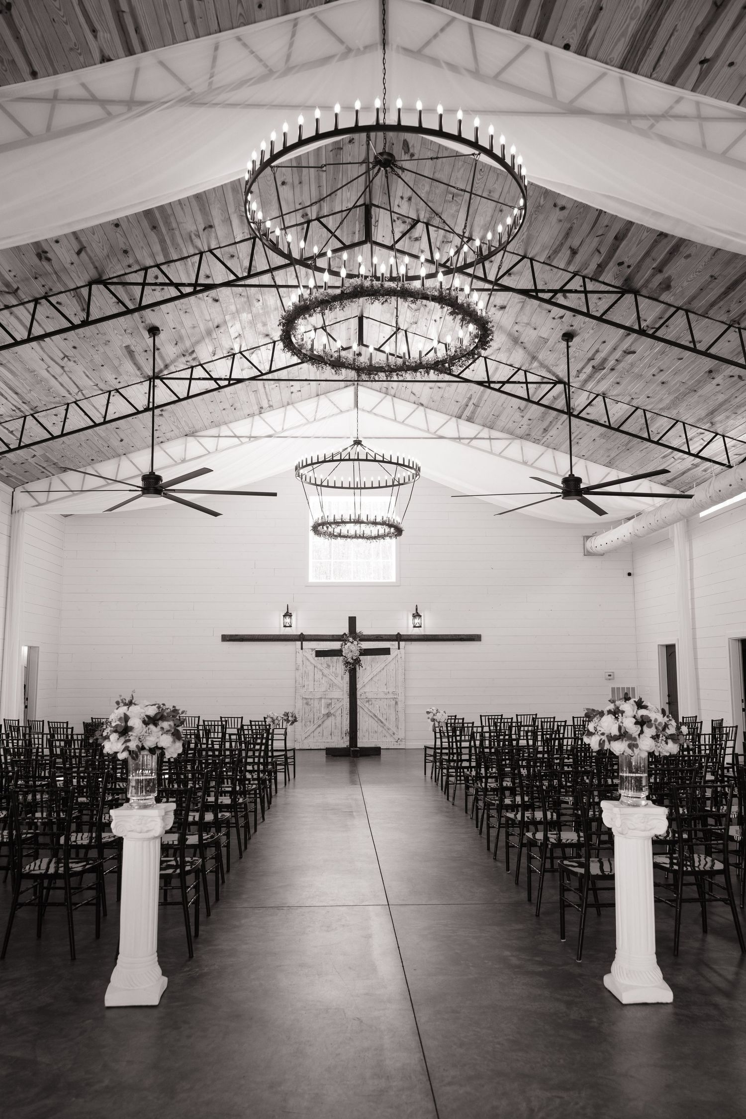 Black and white photo of an elegant church interior with chandeliers and rows of chairs.