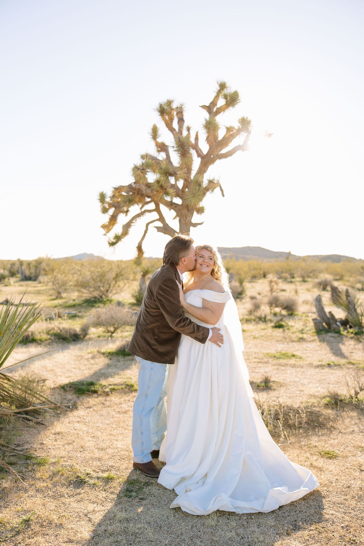 Desert wedding photoshoot with Joshua trees creating a romantic backdrop in golden light.