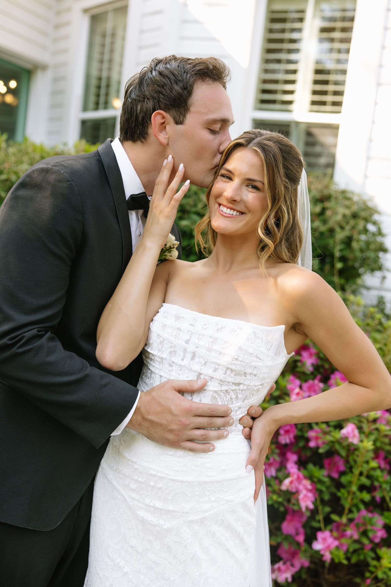 Intimate candid moment between newlyweds by flowering garden.