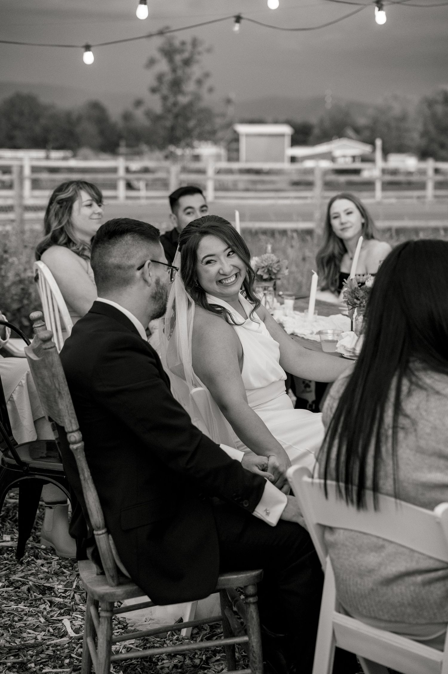 A candid photo of a bride smiling at the groom at their wedding reception at Good Life Farms in Eagle, Idaho