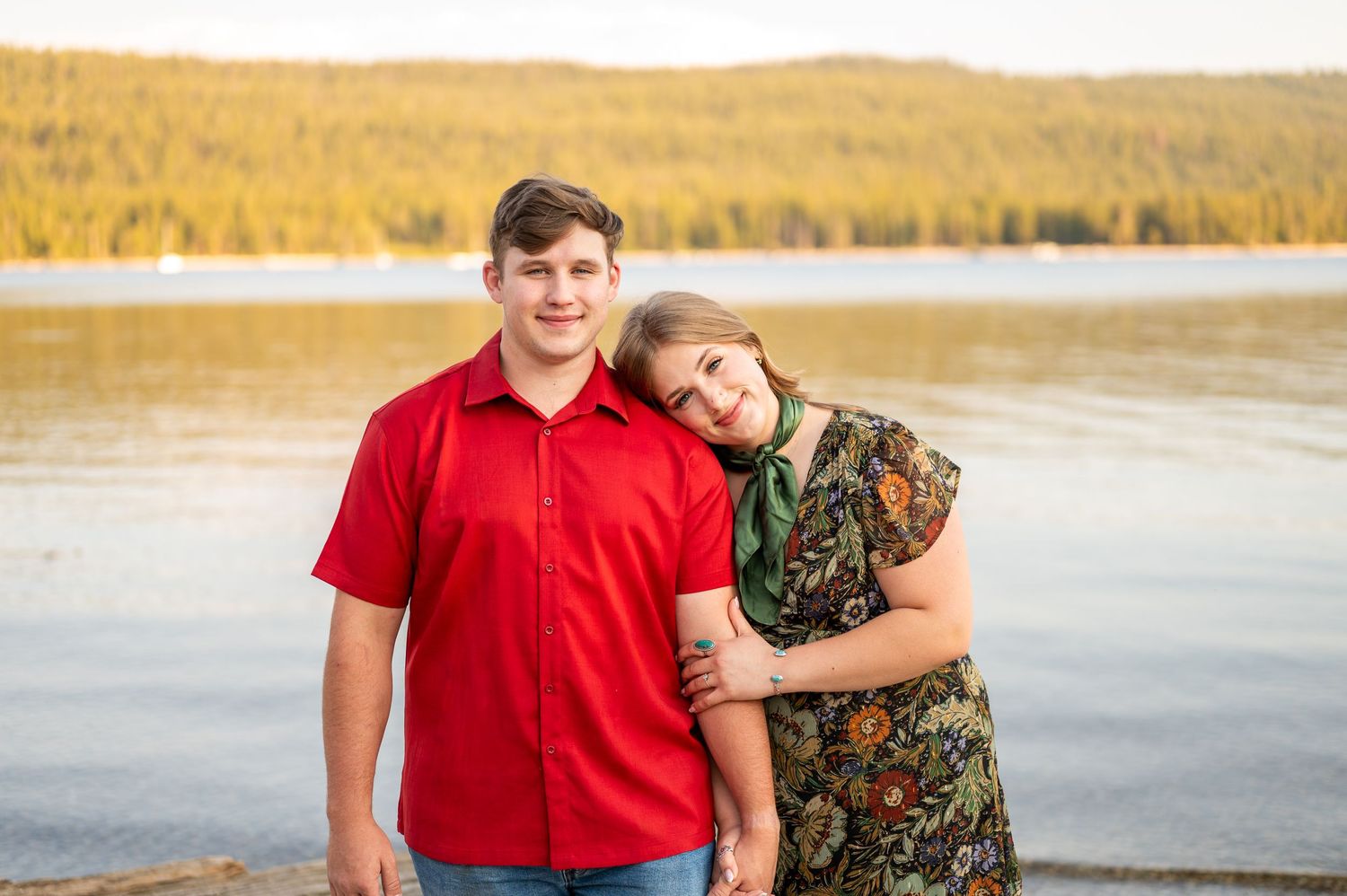 A couple smiles together at the camera in front of Redfish Lake in Stanley, Idaho.