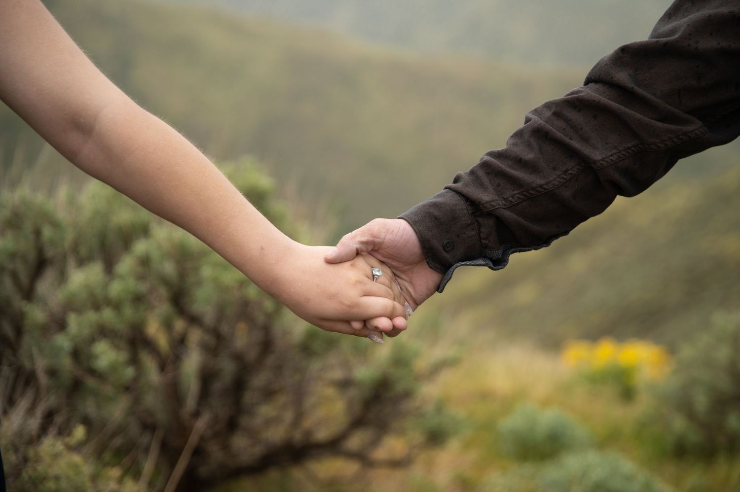 a couple holding hands featuring an engagement ring.
