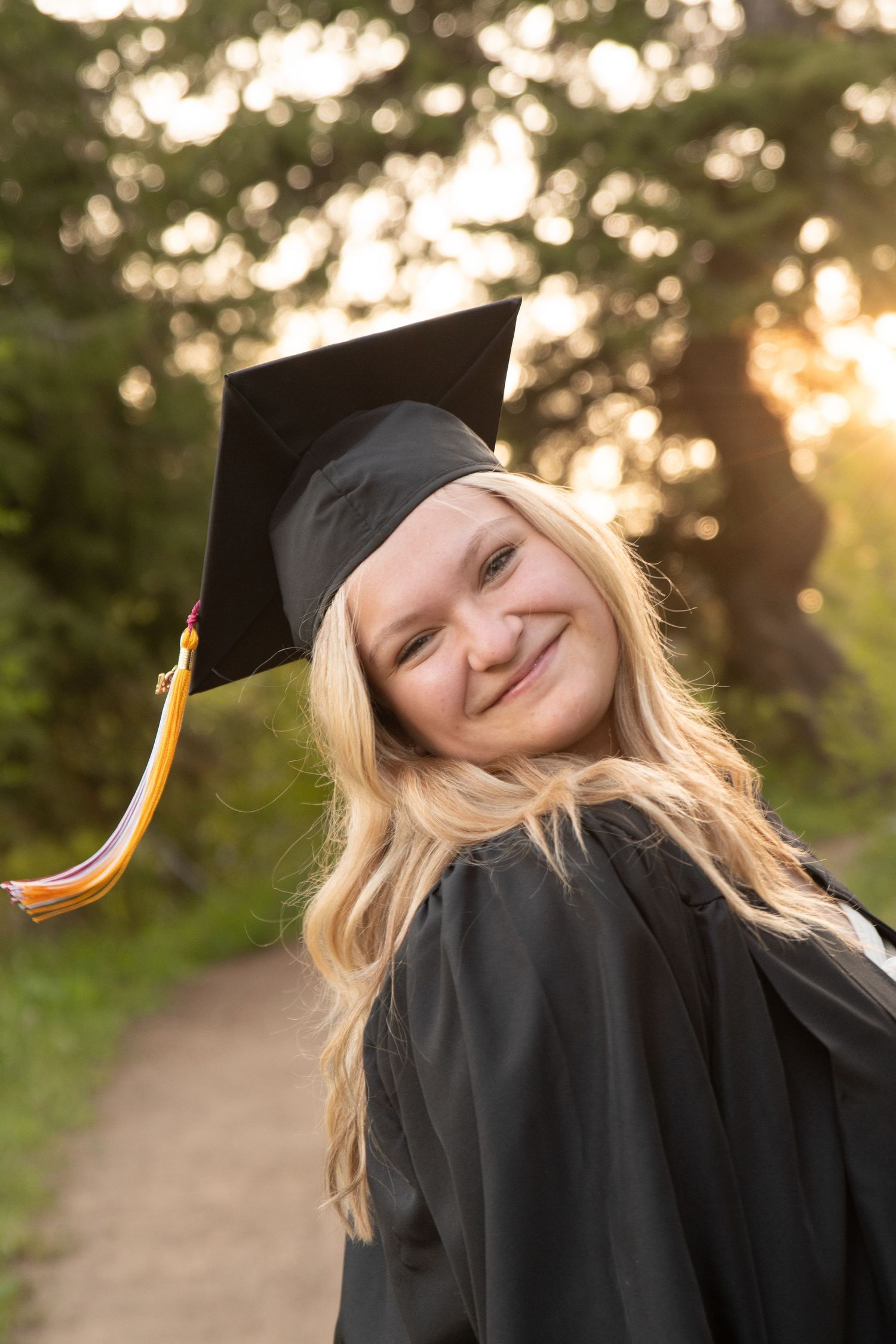 A graduating senior in cap and gown smiles at the camera during senior photos in Boise, Idaho.