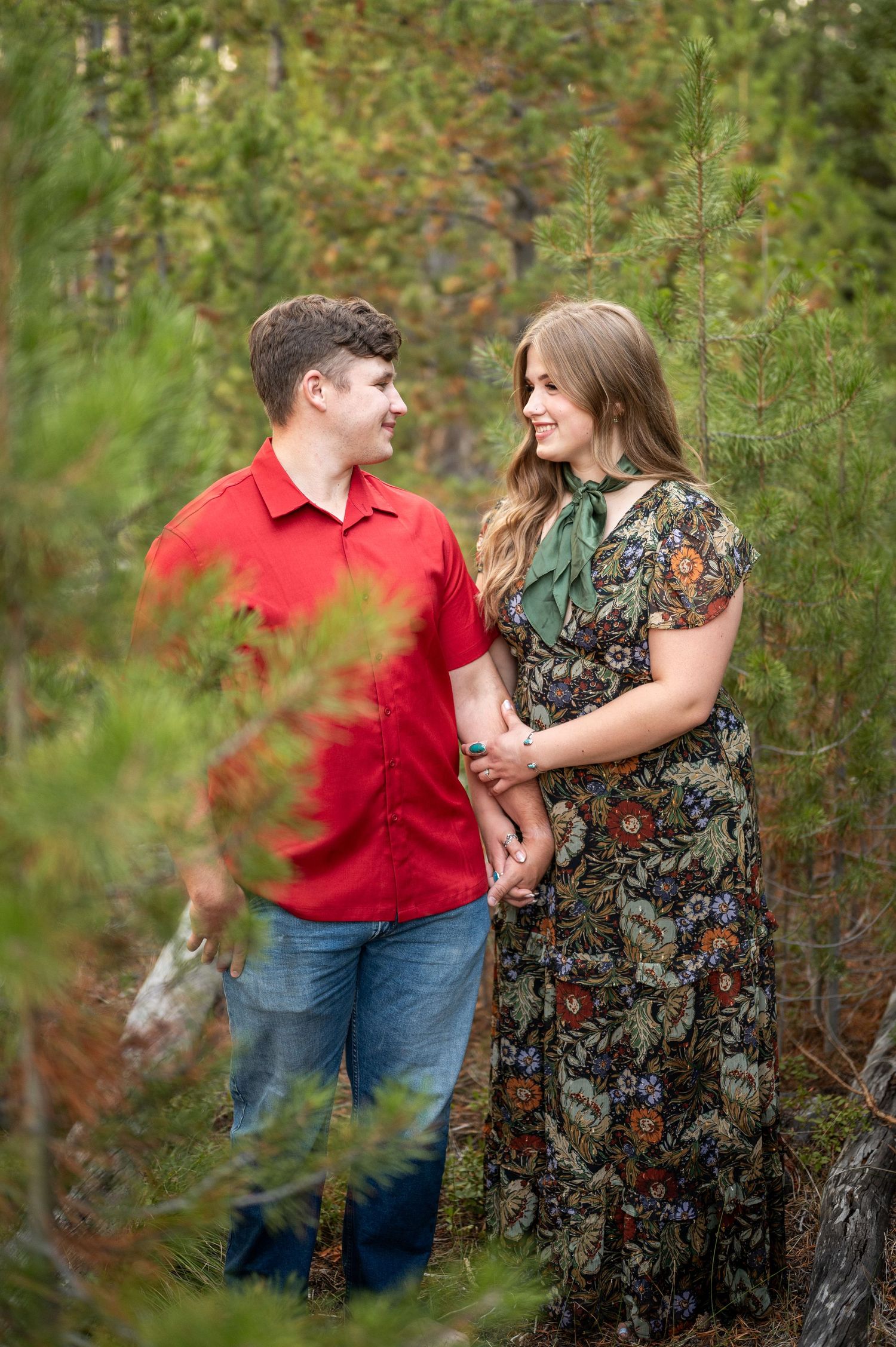 A couple smiling at each other while surrounded by trees in a national forest near Stanley, Idaho.