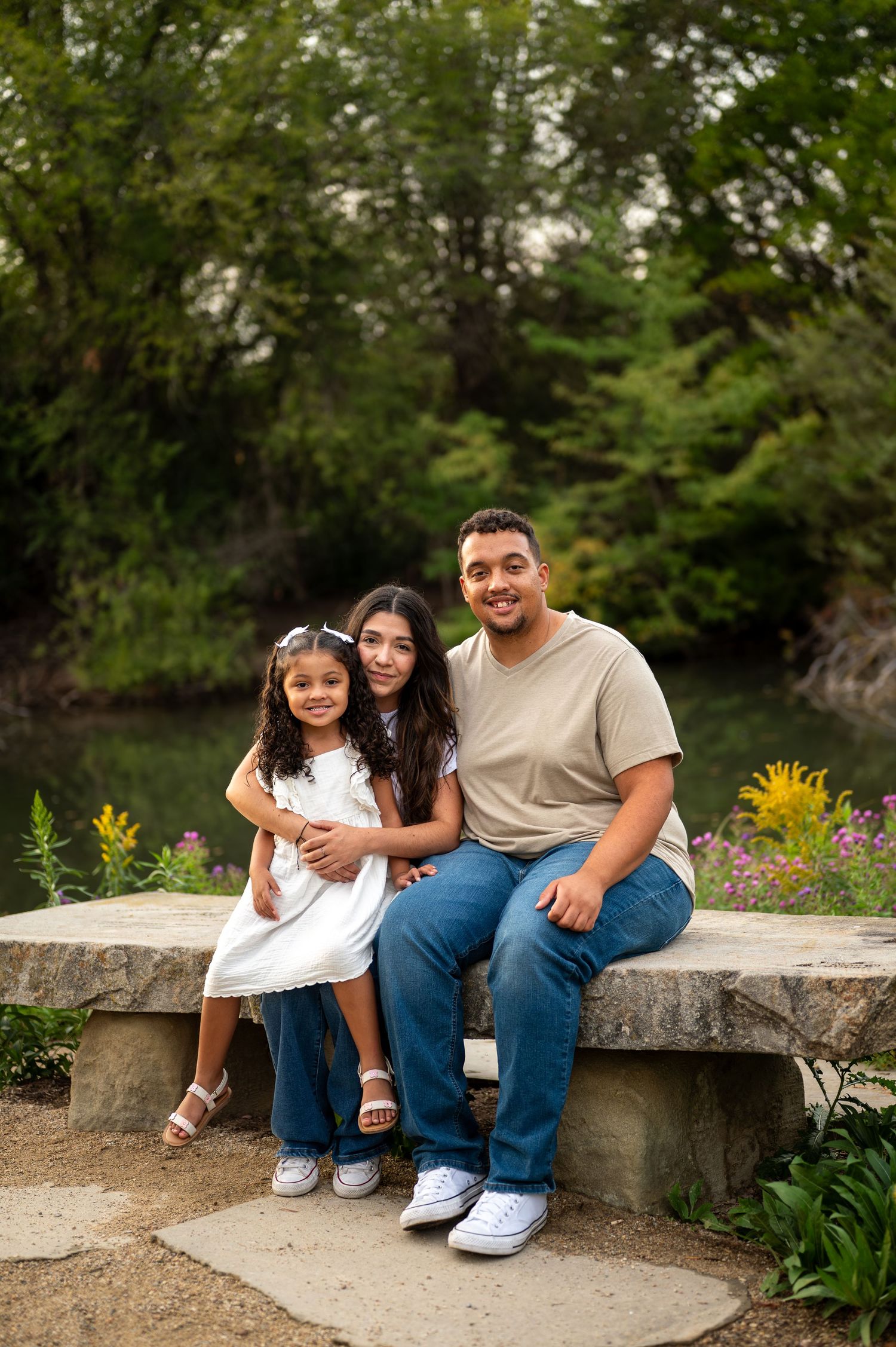 A family of 3 poses in front of a pretty pond in Boise, Idaho.