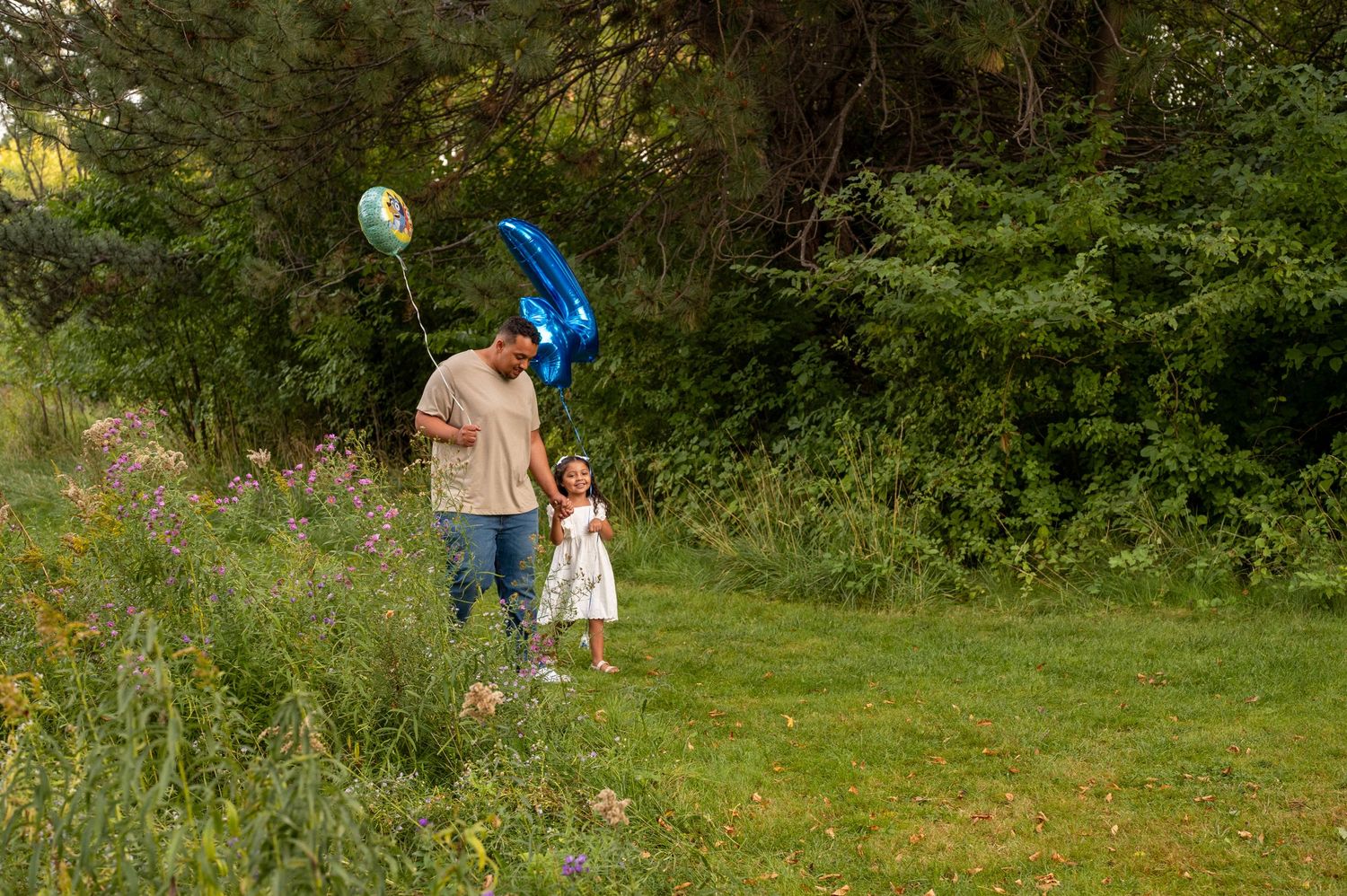 a candid moment of a dad and daughter during her 4th birthday photoshoot walking with balloons. Boise, Idaho.