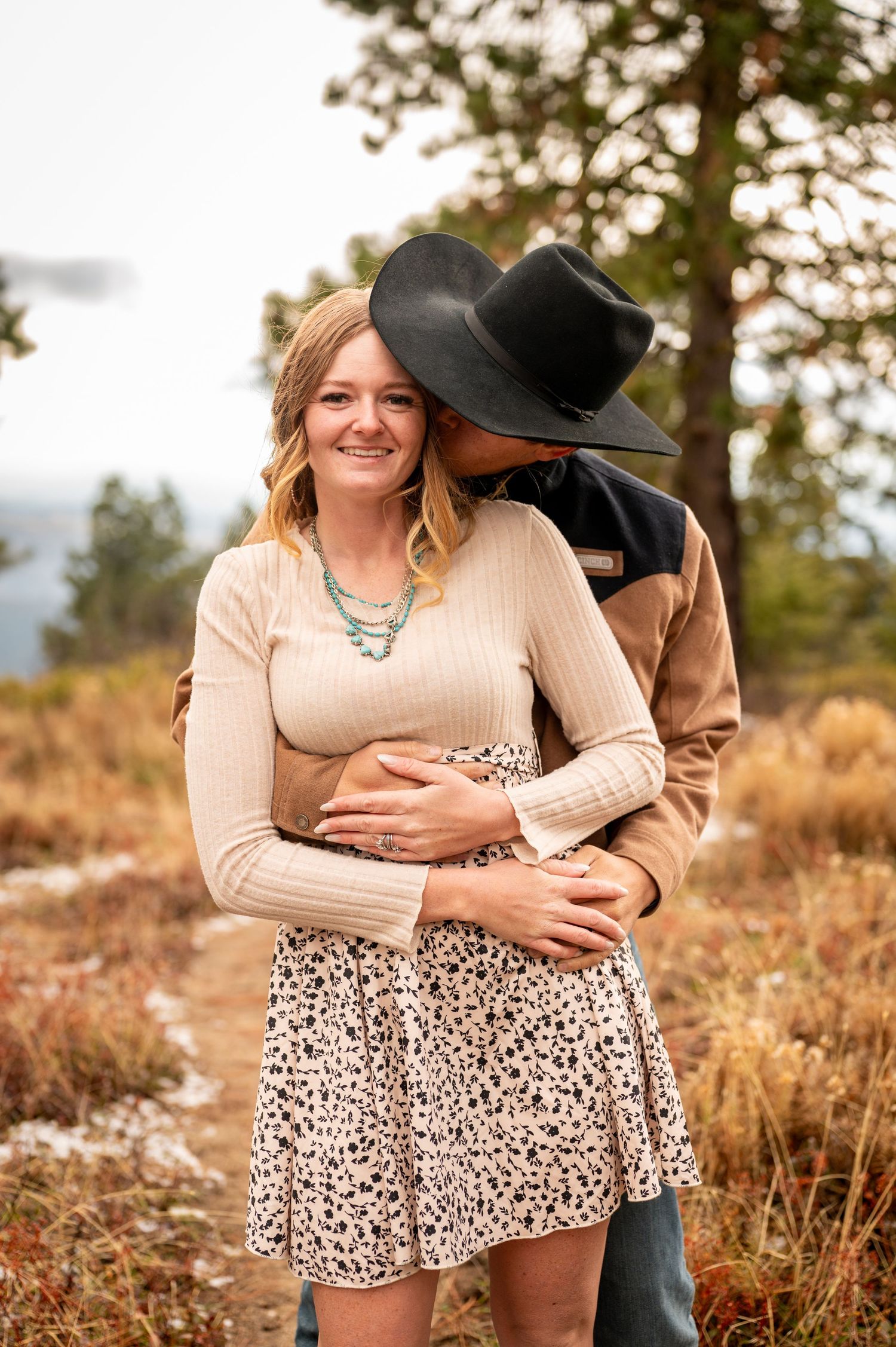 A cowboy kisses the cheek of his fiancé in the mountains of boise, Idaho.