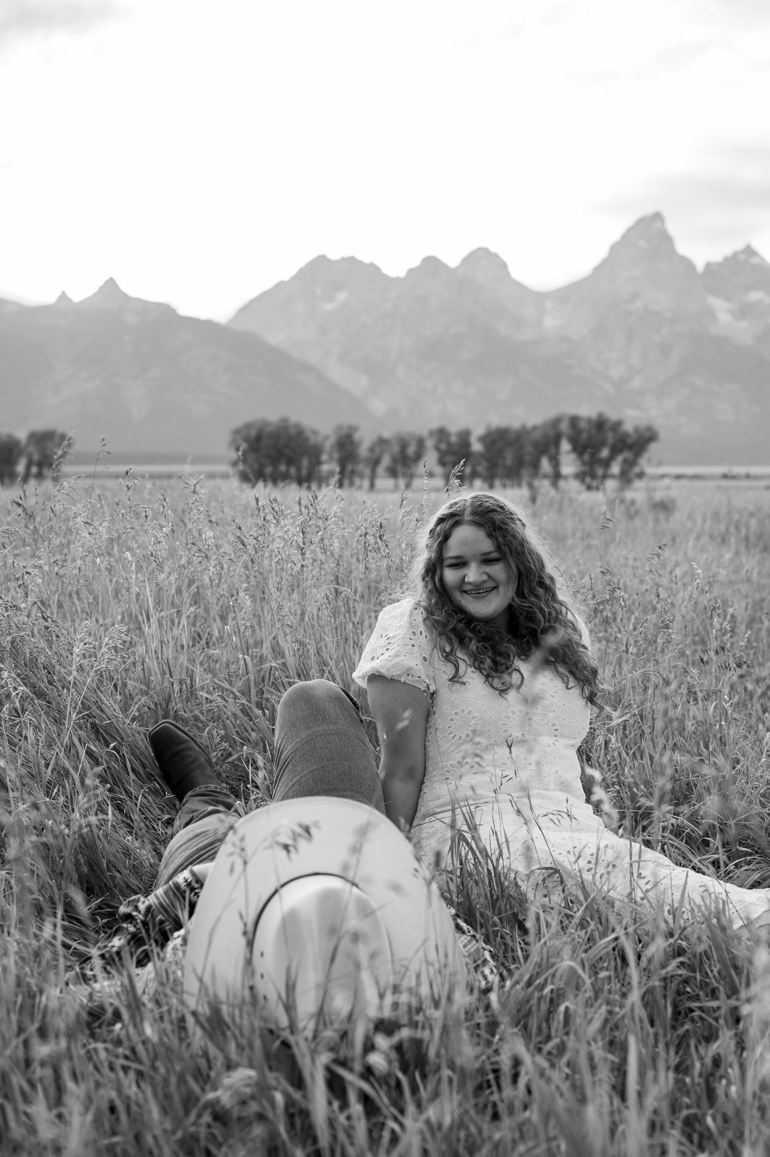 A couple laying in the tall grass at mormon row in Grand Teton national park