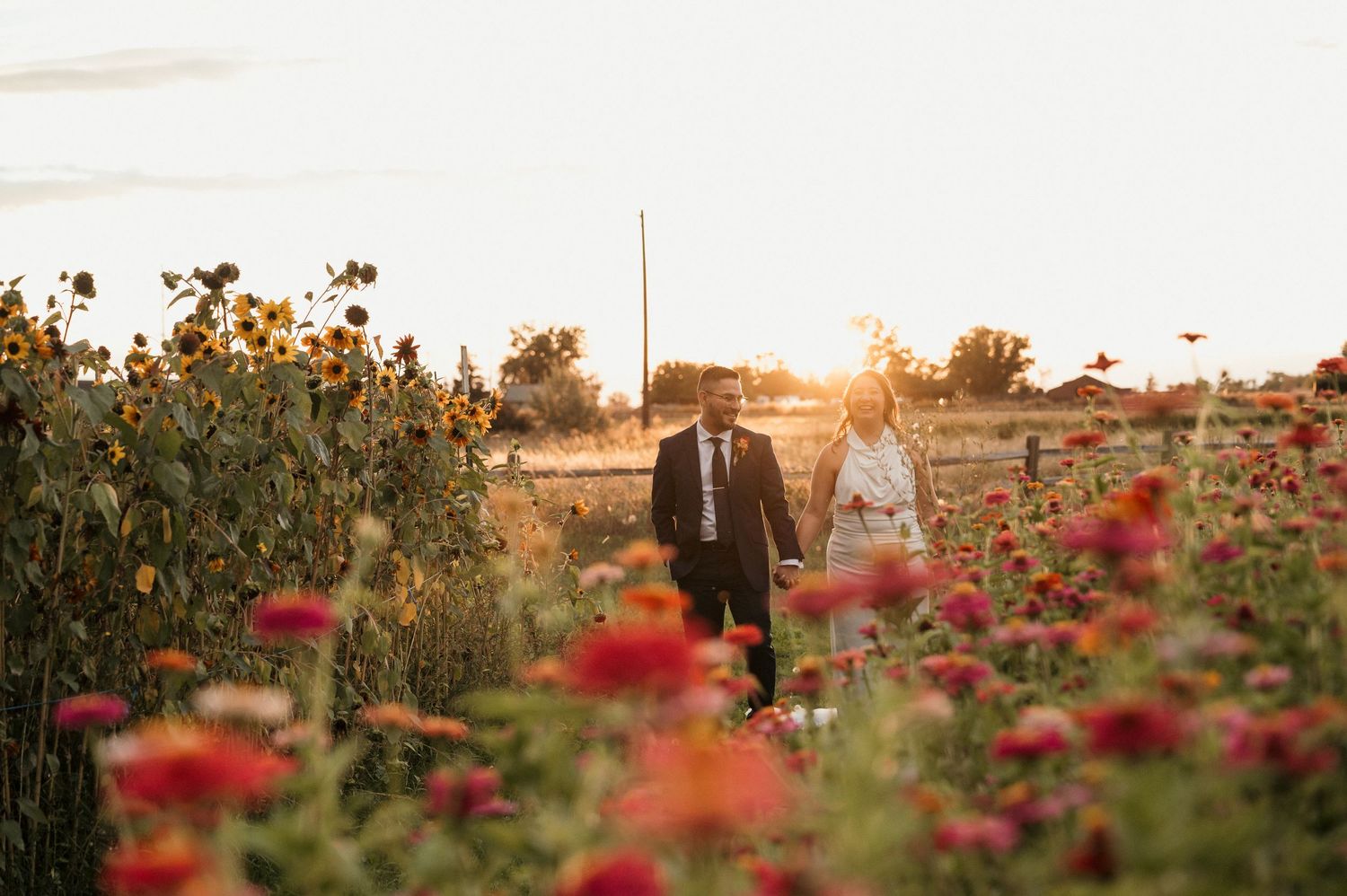 Bride and groom walking in a flower field during golden hour at Good Life Farms in Eagle, Idaho, during their wedding reception.