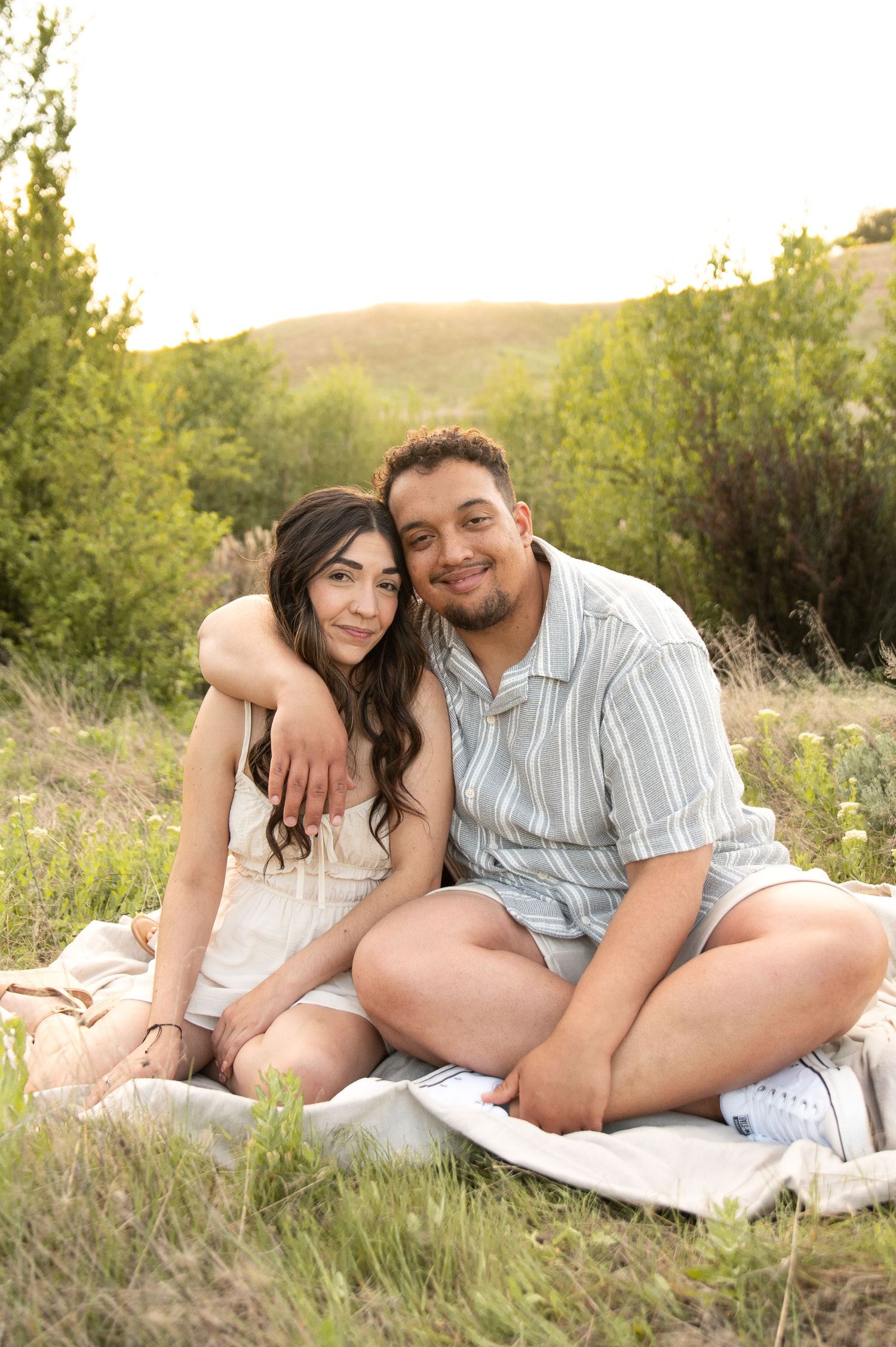 A couple poses on a blanket at golden hour in Boise, Idaho.