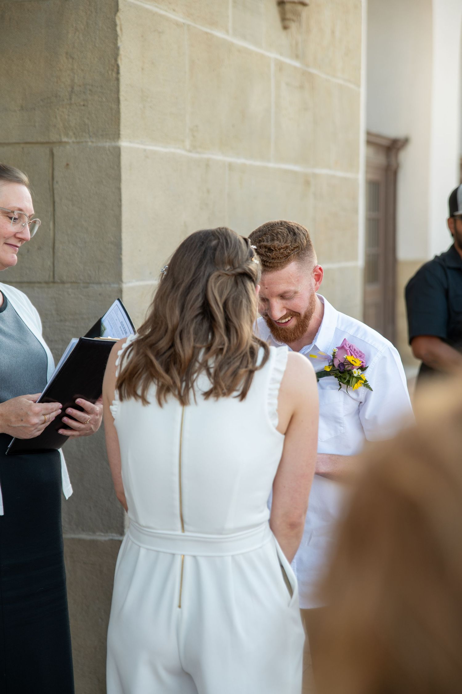 A bride and groom laughing together while reading their vows outside the Boise Train Depot in Boise, Idaho.