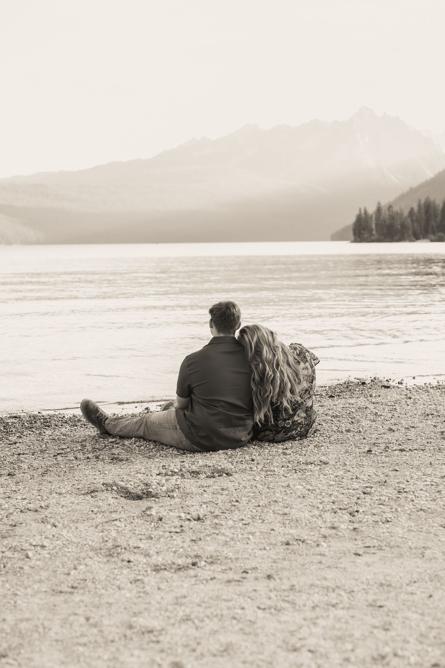 A cinematic shot of a couple sitting together looking at the water in Stanley Idaho.