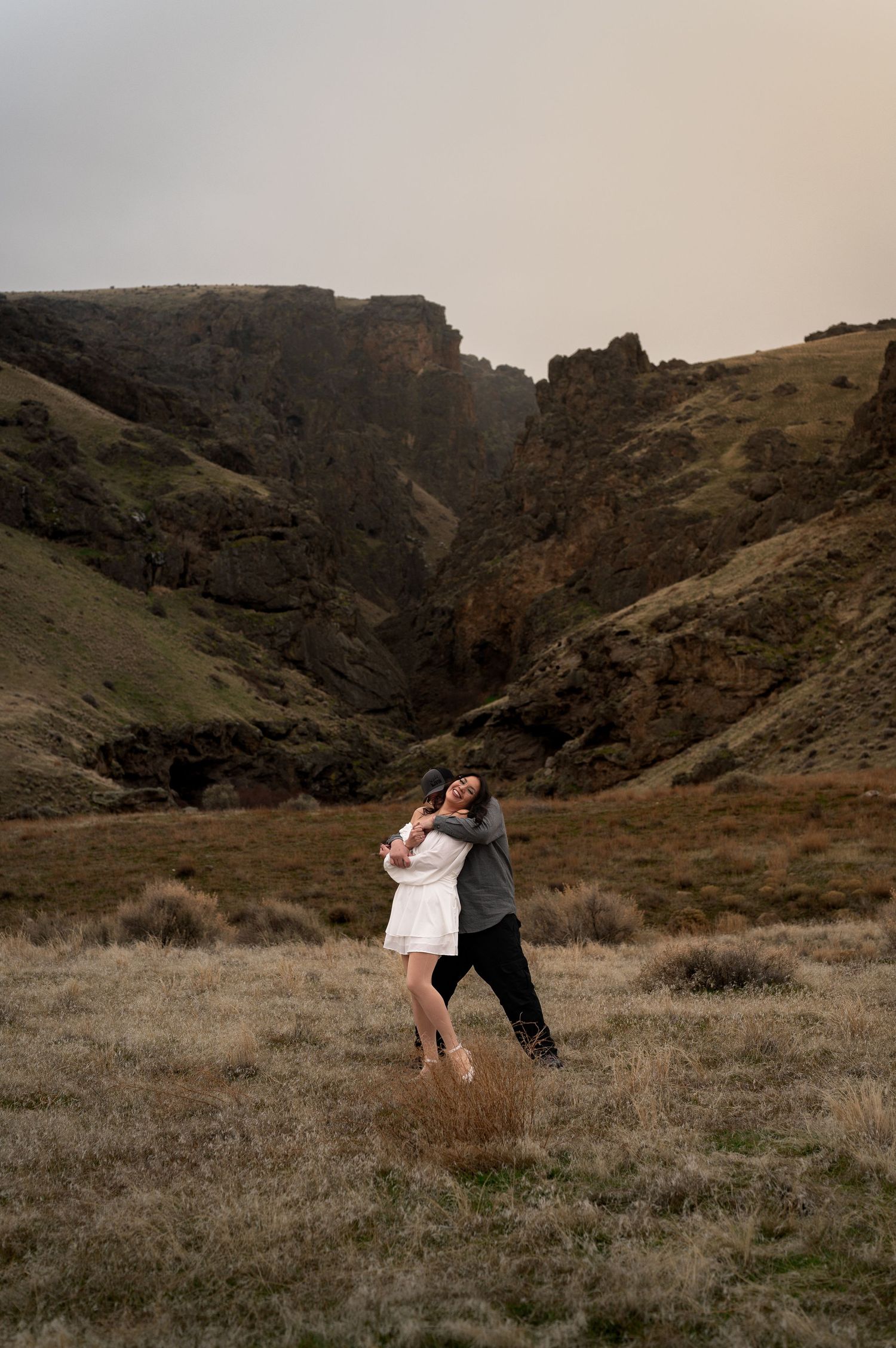 a couple snuggled up together during their engagement shoot at jump creek trailhead in marsing, idaho.
