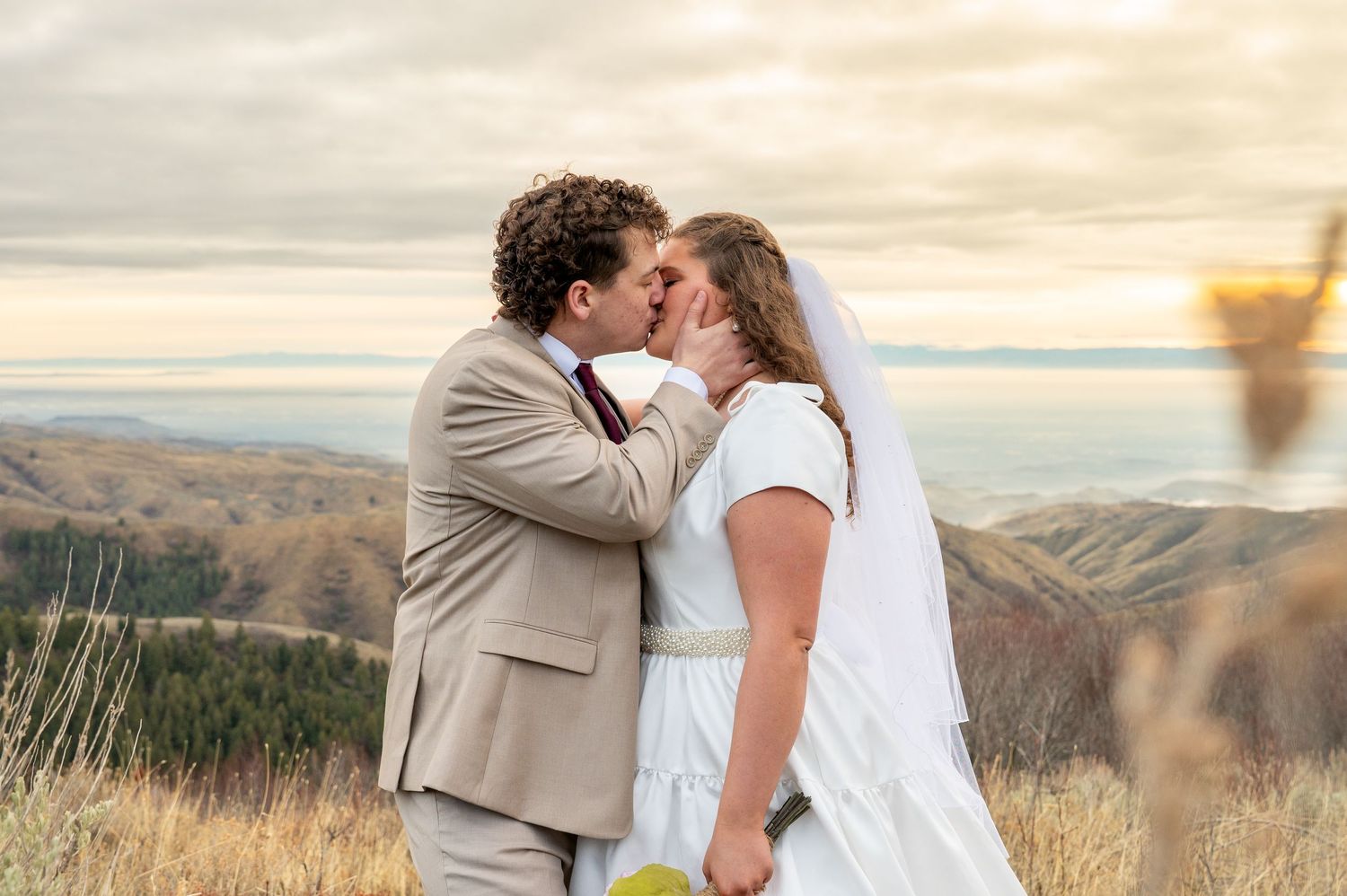 A Newly married couple kissing after their first look with mountain views in Boise, Idaho.