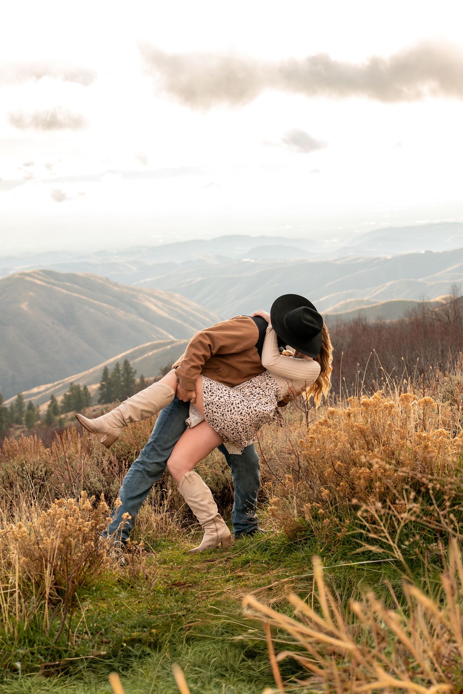 A cowboy kisses his fiancé with mountain views in Boise, Idaho.