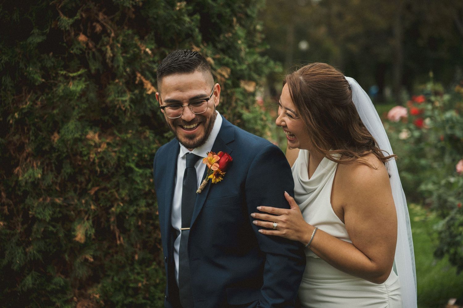 A bride and groom share a candid laugh moment after their wedding at the Rose Gardens in Boise, Idaho.