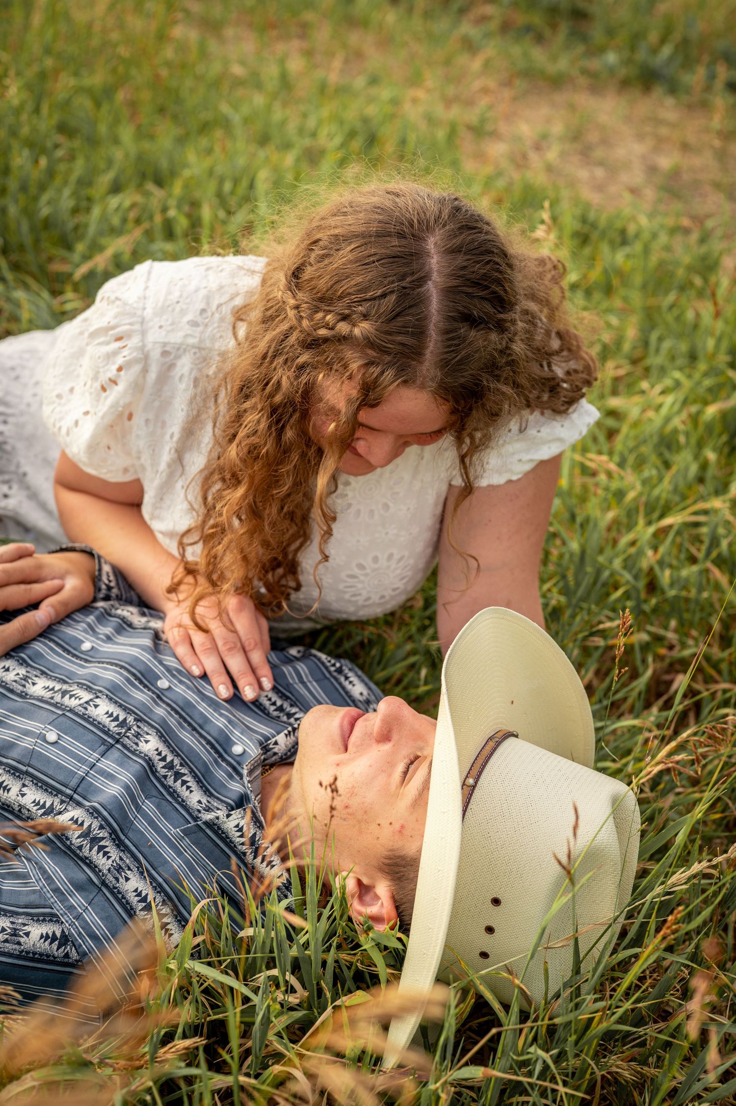 A photo of a couple laying in the grass at Mormon Row in Grand Teton National Park .