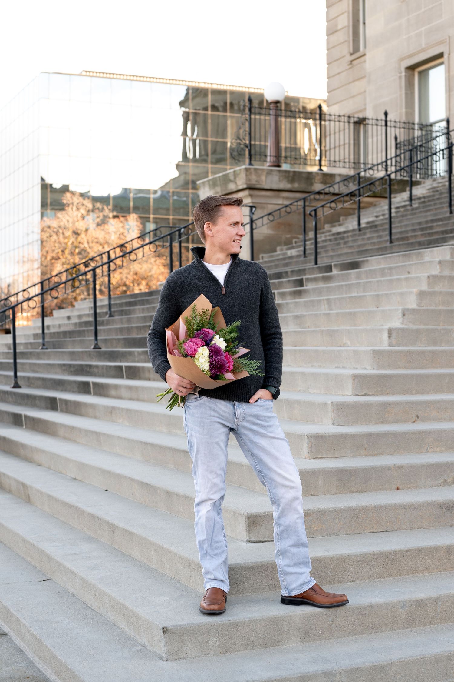 A man holding a bouquet of flowers on the steps of a building in downtown Boise, Idaho.