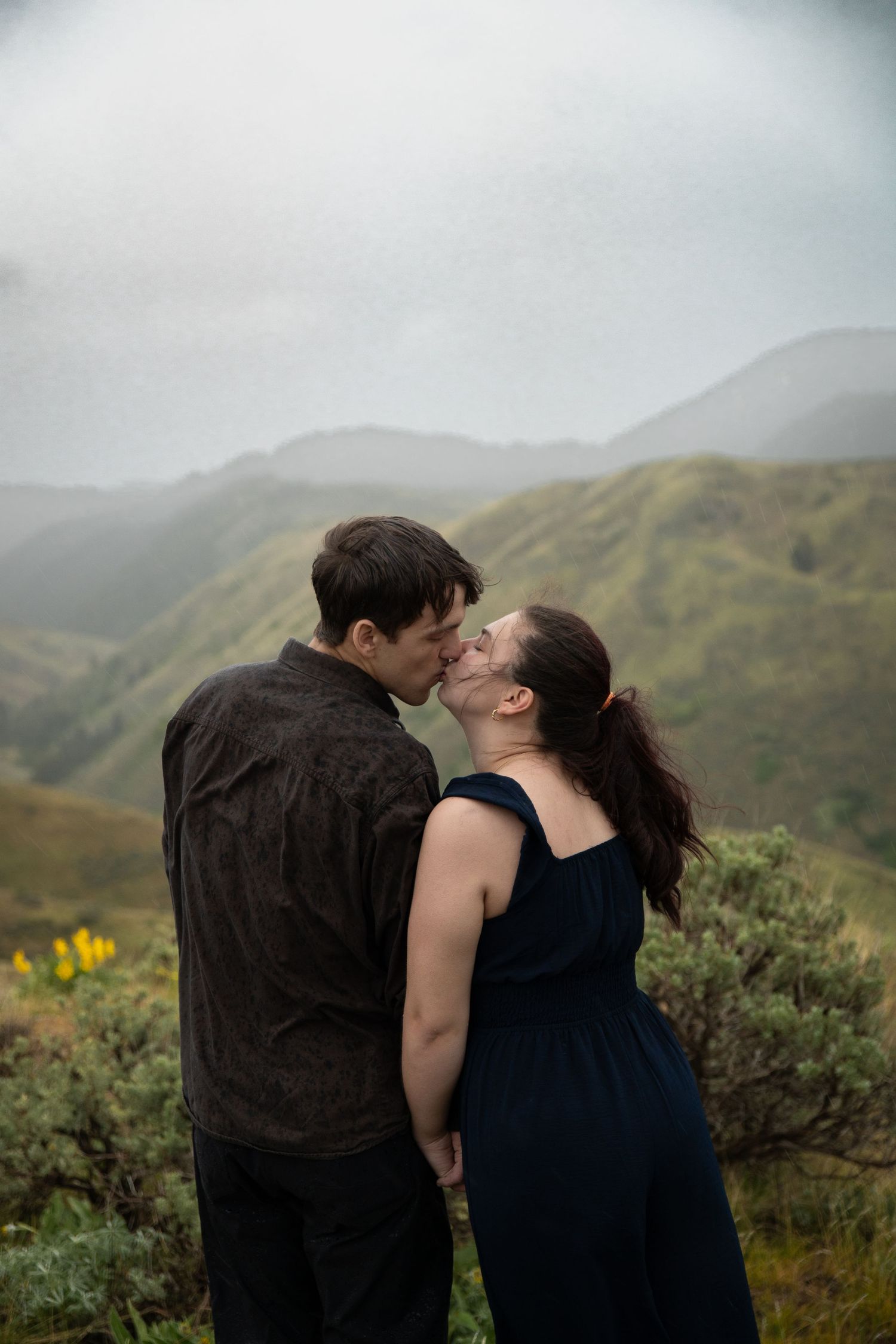 A couple kissing while overlooking the mountains during a rainy shoot in Boise, Idaho.