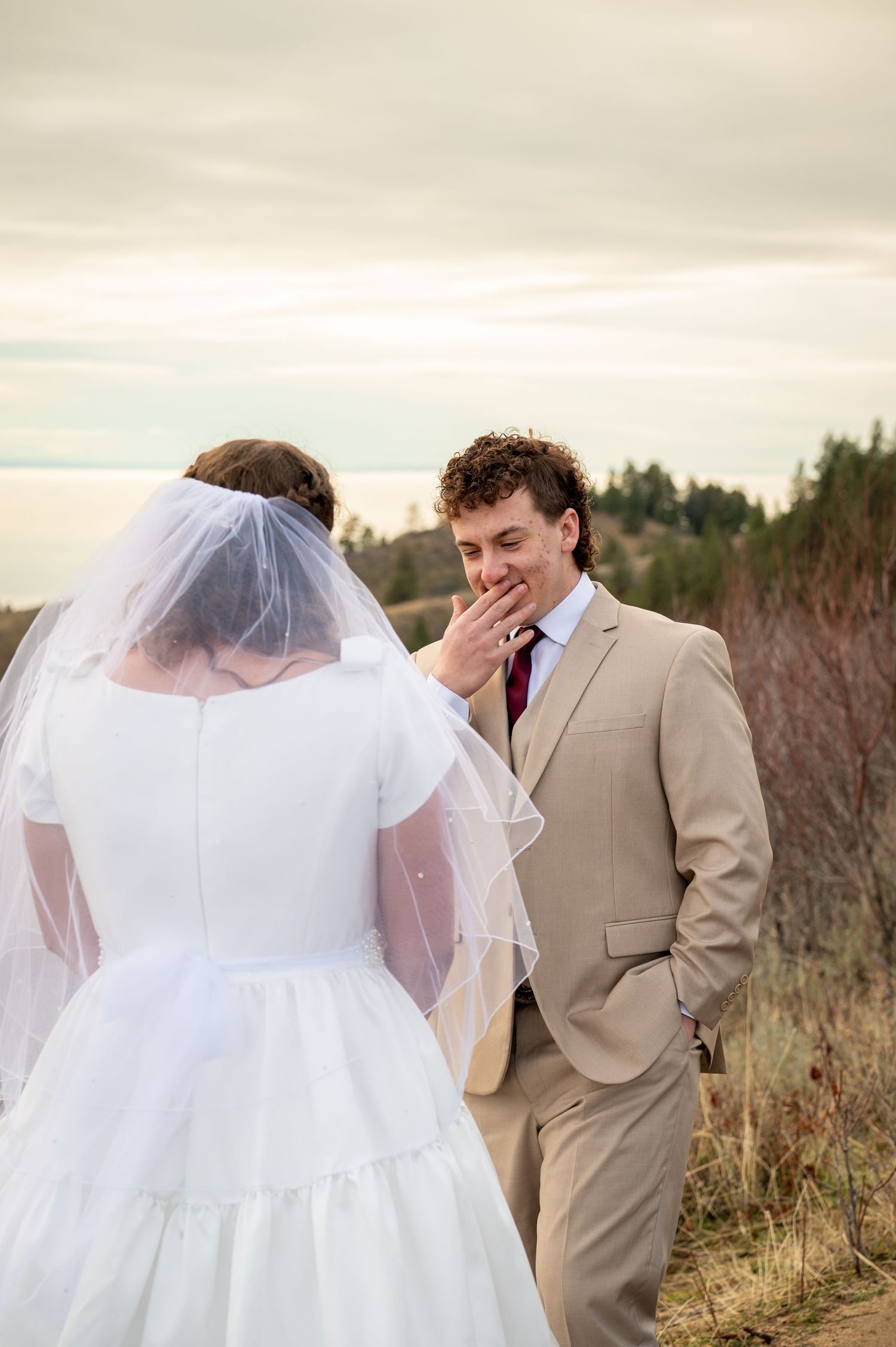 An emotional and happy groom seeing his bride in their first look with a beautiful sunset view in Boise, Idaho.