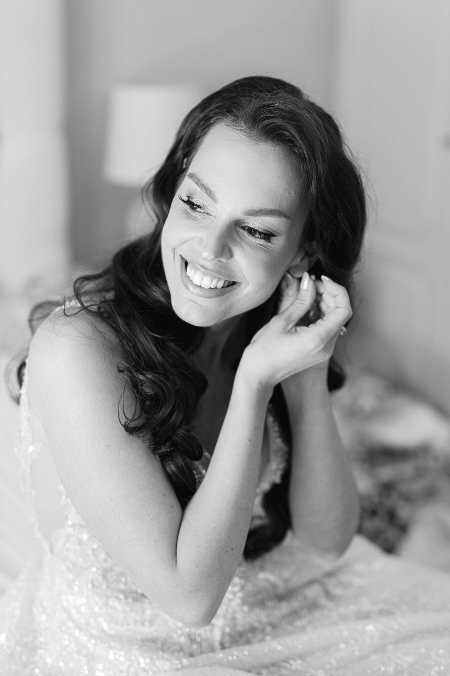Black and white portrait of bride with wavy dark hair and joyful expression.