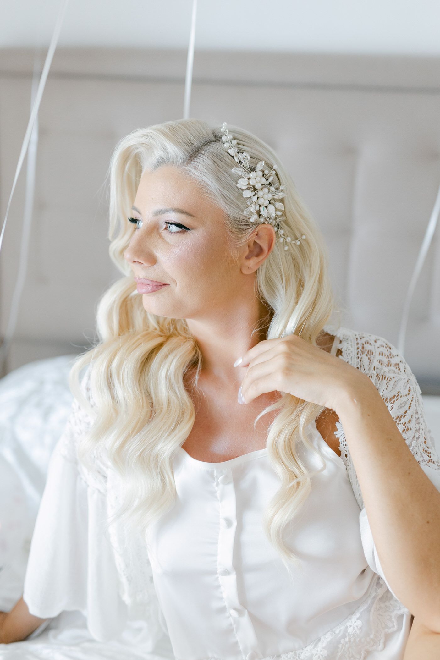 Beautiful platinum blonde bridal hairstyle with pearl and crystal hair accessory in soft natural lighting.