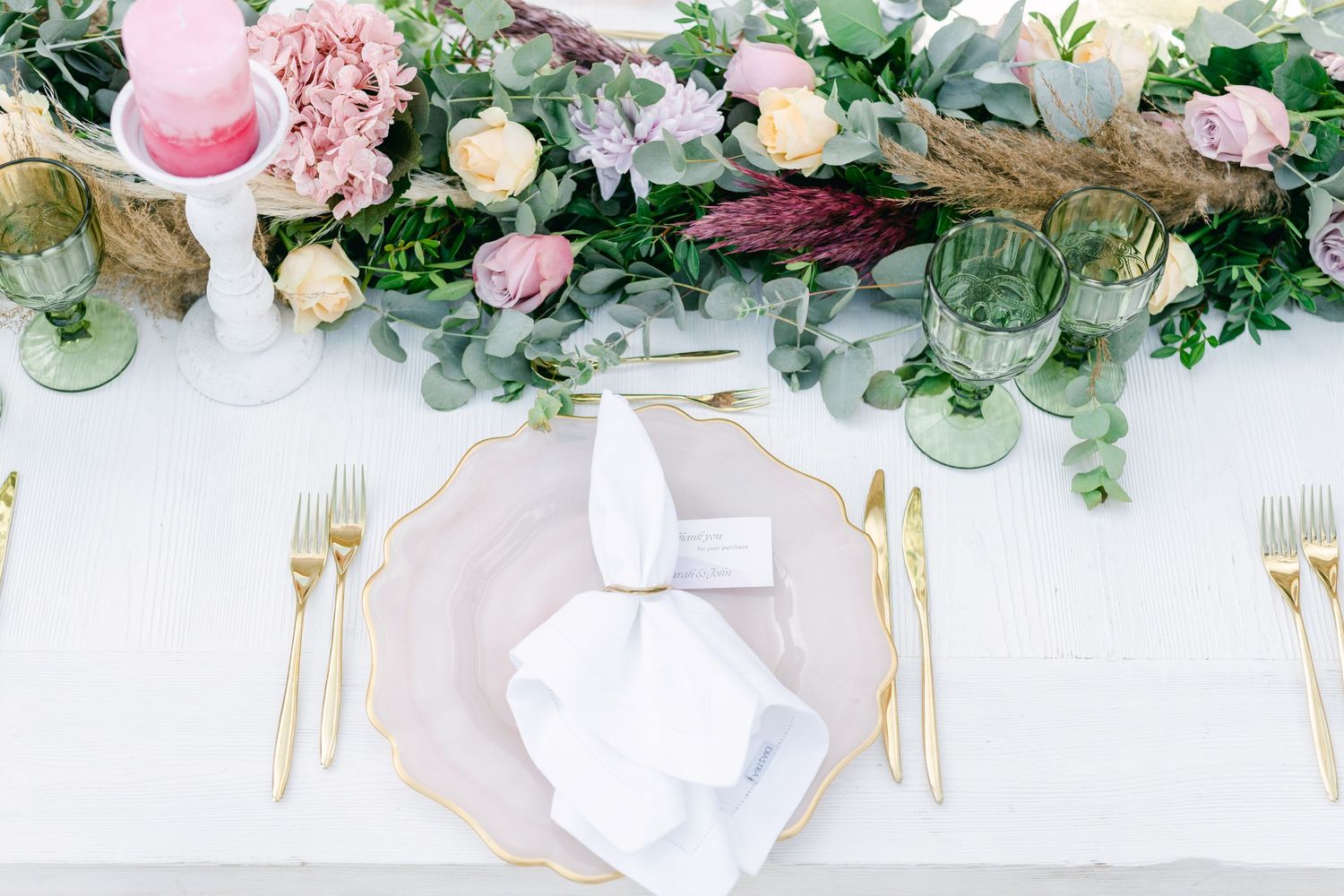 Elegant wedding table setting with pink flowers and gold cutlery.