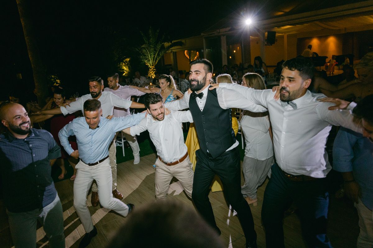 A group of wedding guests jumping and dancing together during an evening reception celebration.