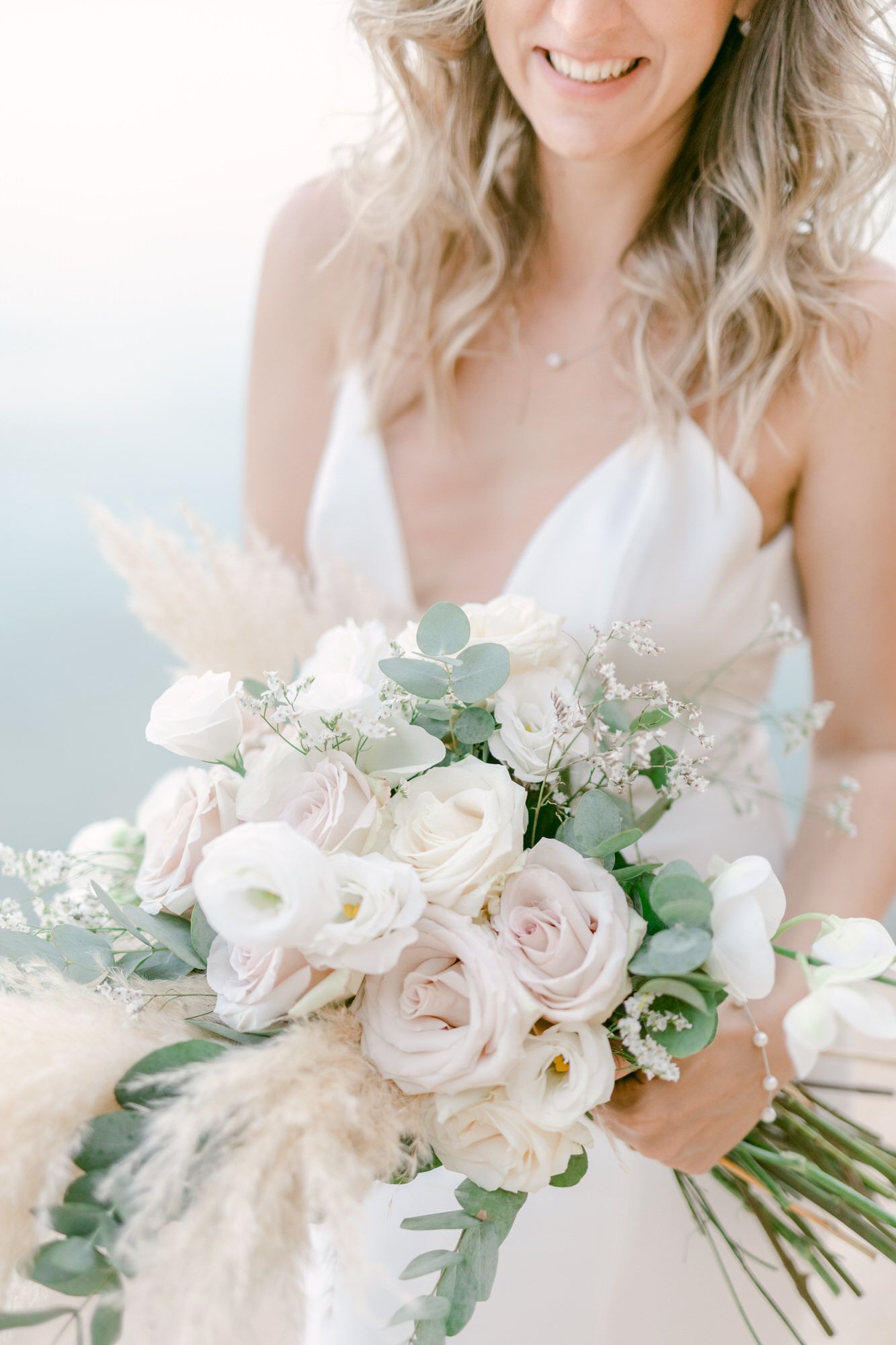 A delicate bridal bouquet with white roses, pink accents and eucalyptus leaves.