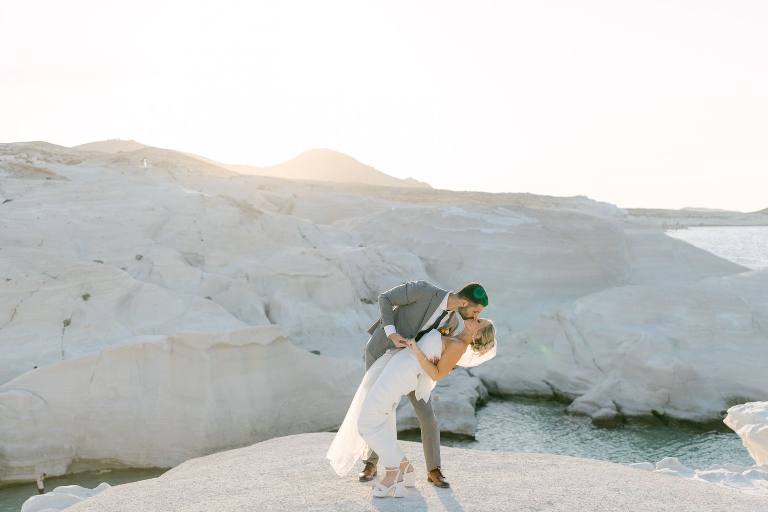 Destination wedding portraits on the Greek island of Milos Sarakiniko coastline in warm evening light.