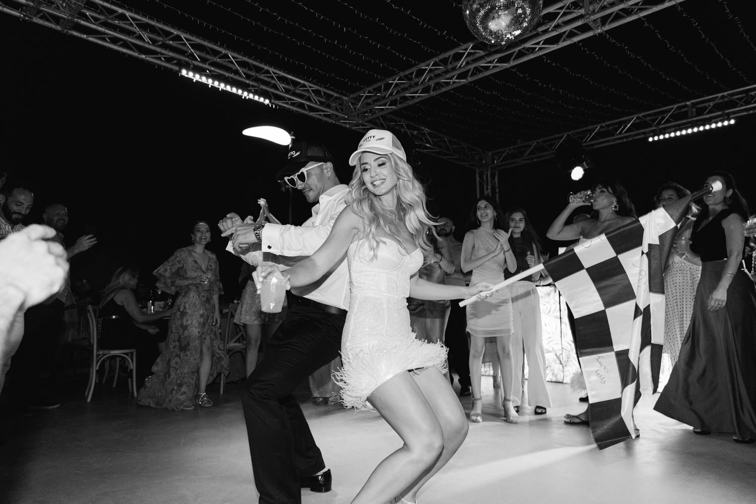 Dancing guests in vintage black and white photo enjoying themselves at a lively party with lights and decor.