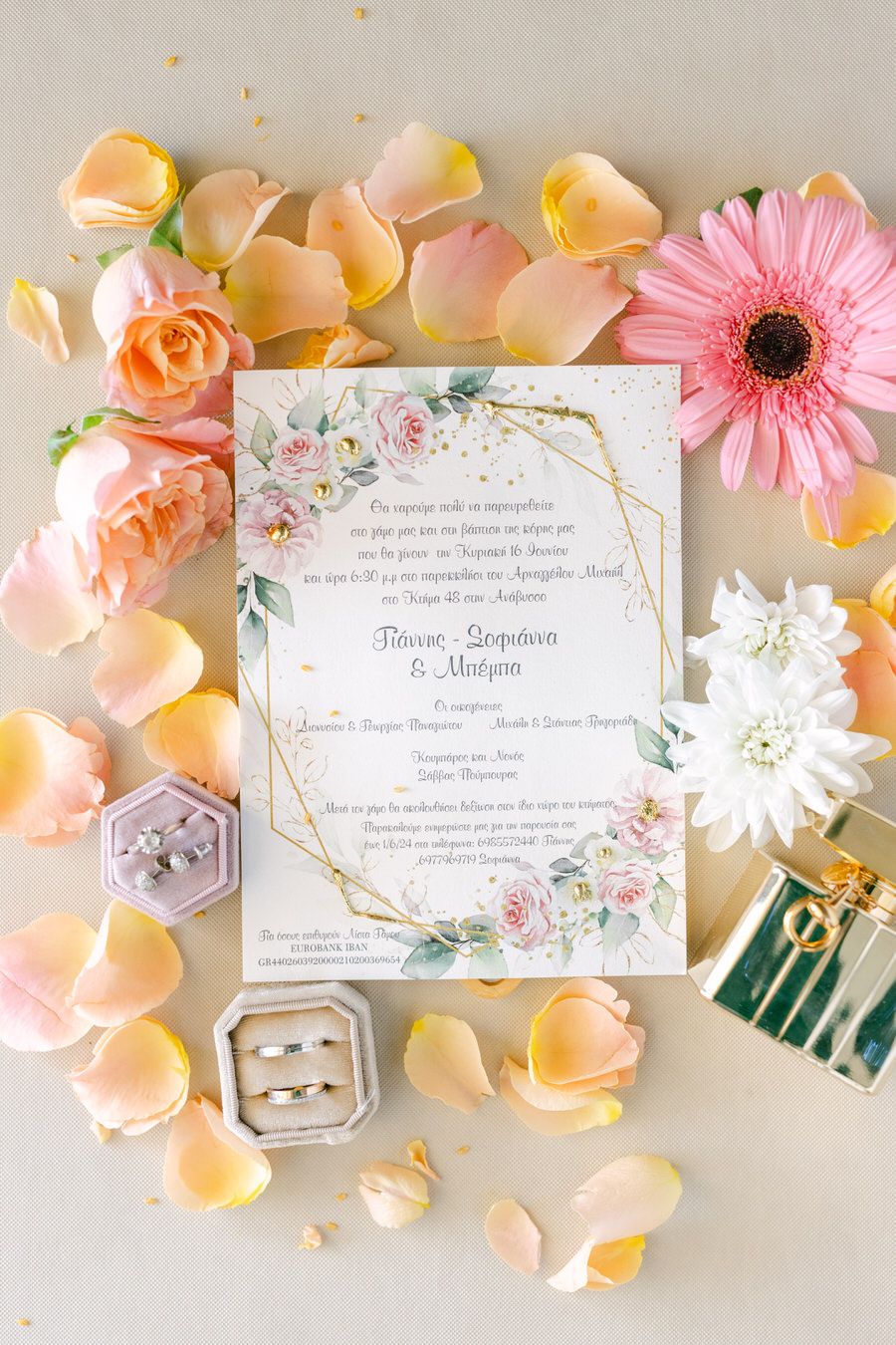 Wedding invitation with floral design surrounded by pink rose petals and gerbera daisy.