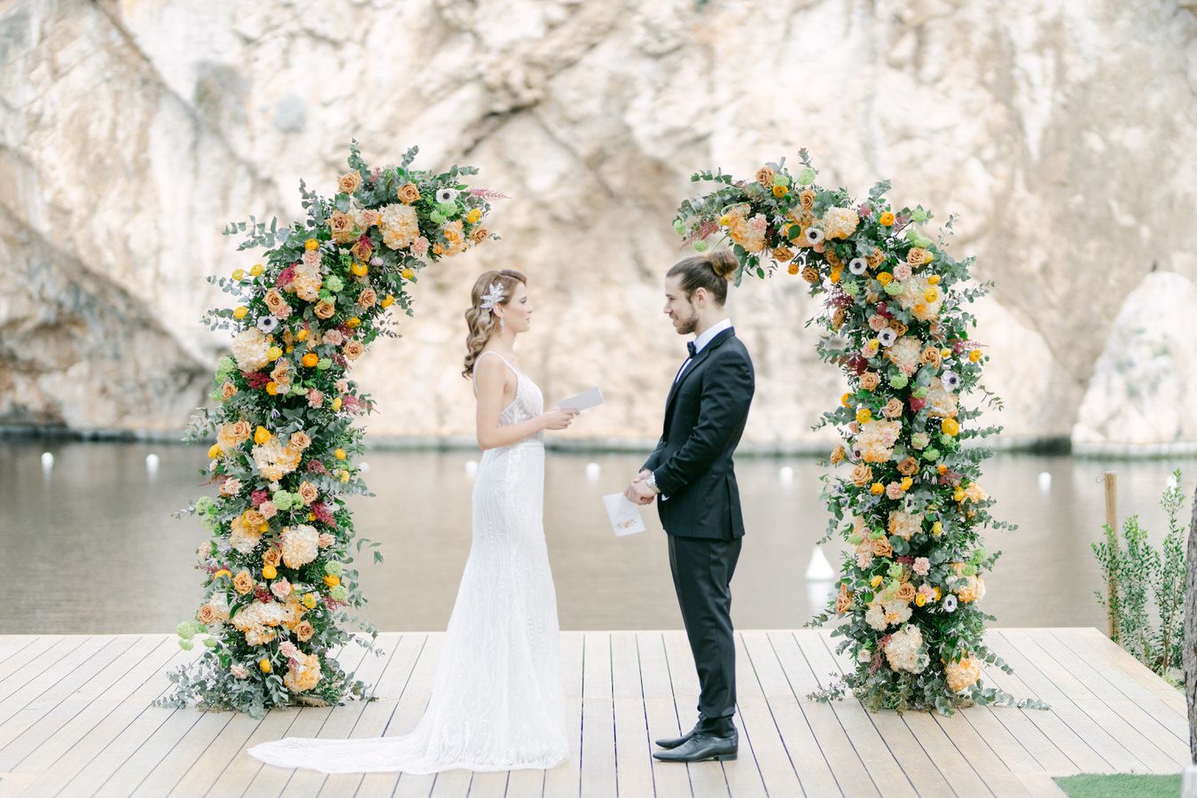 Vouliagmeni Lake wedding in Greece with floral ceremony setting and elegant couple portrait