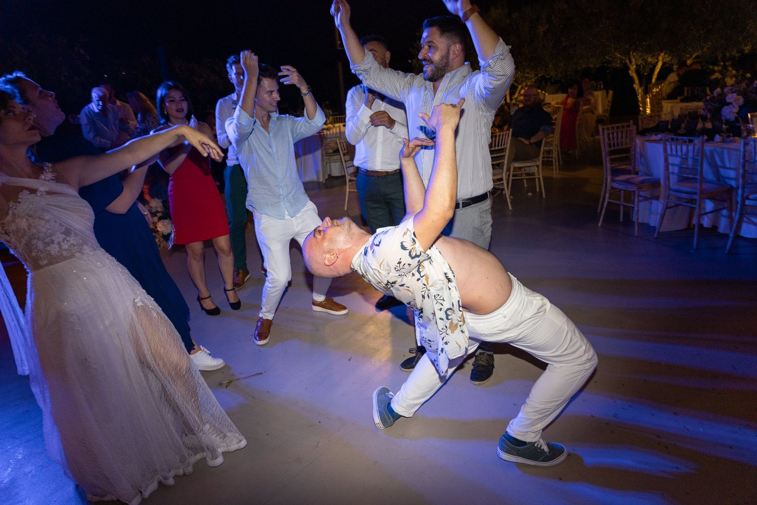 Energetic dancers perform dynamic dance moves on an illuminated dance floor at a wedding reception.