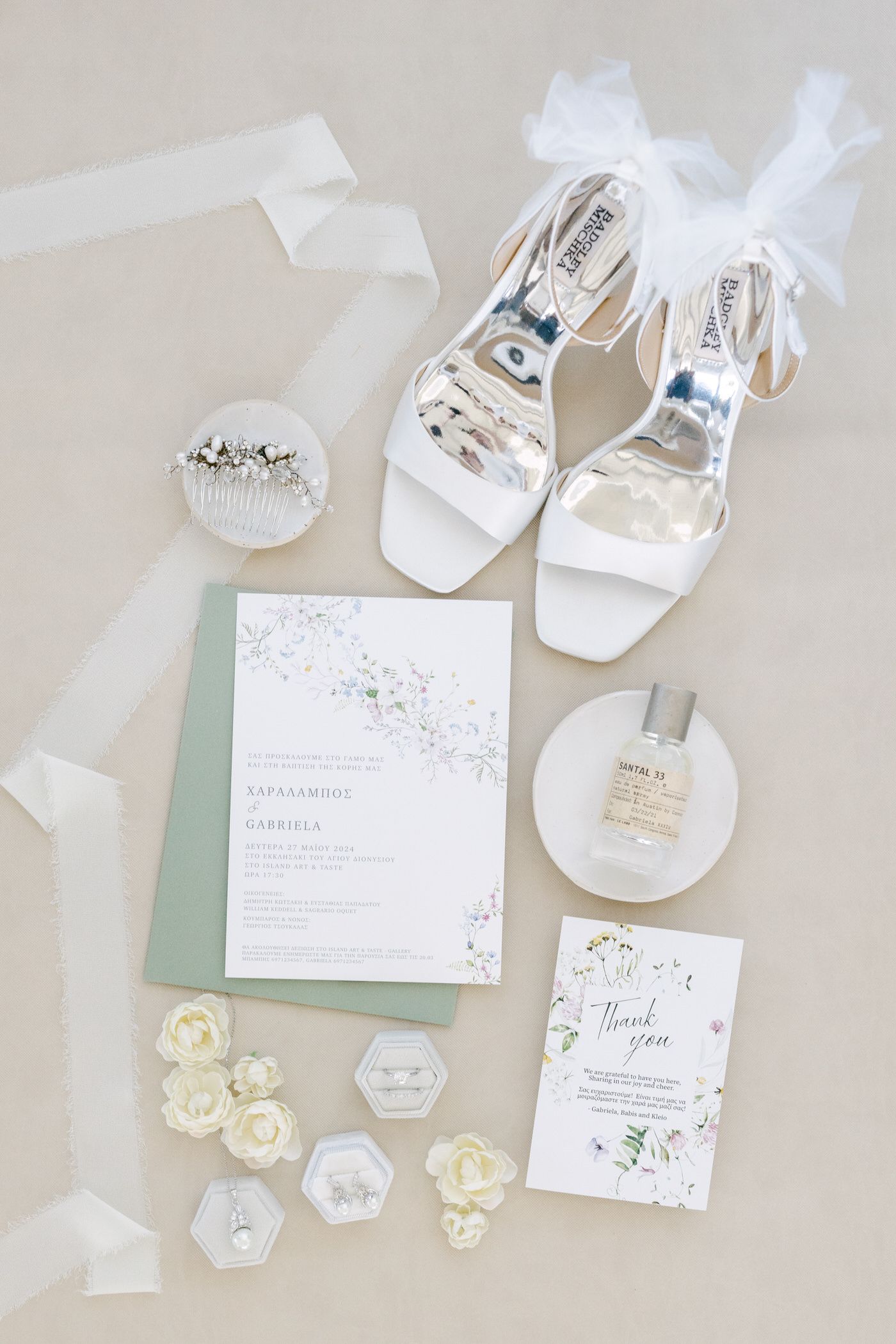 Elegant white wedding accessories featuring bridal shoes, floral invitations, perfume bottles and delicate ribbon accents.