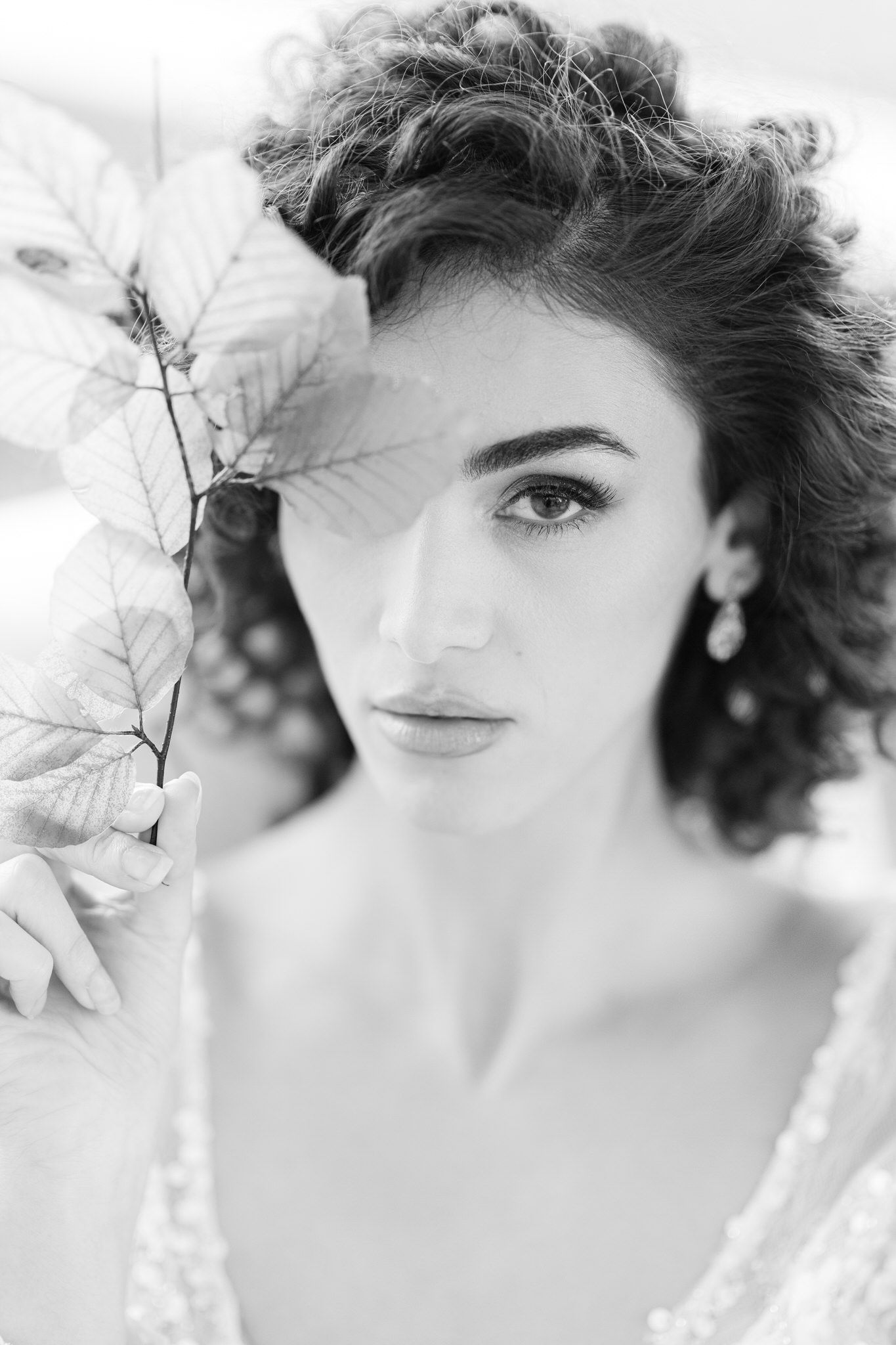 Black and white portrait featuring dramatic lighting, delicate floral elements, and vintage-inspired elegance.