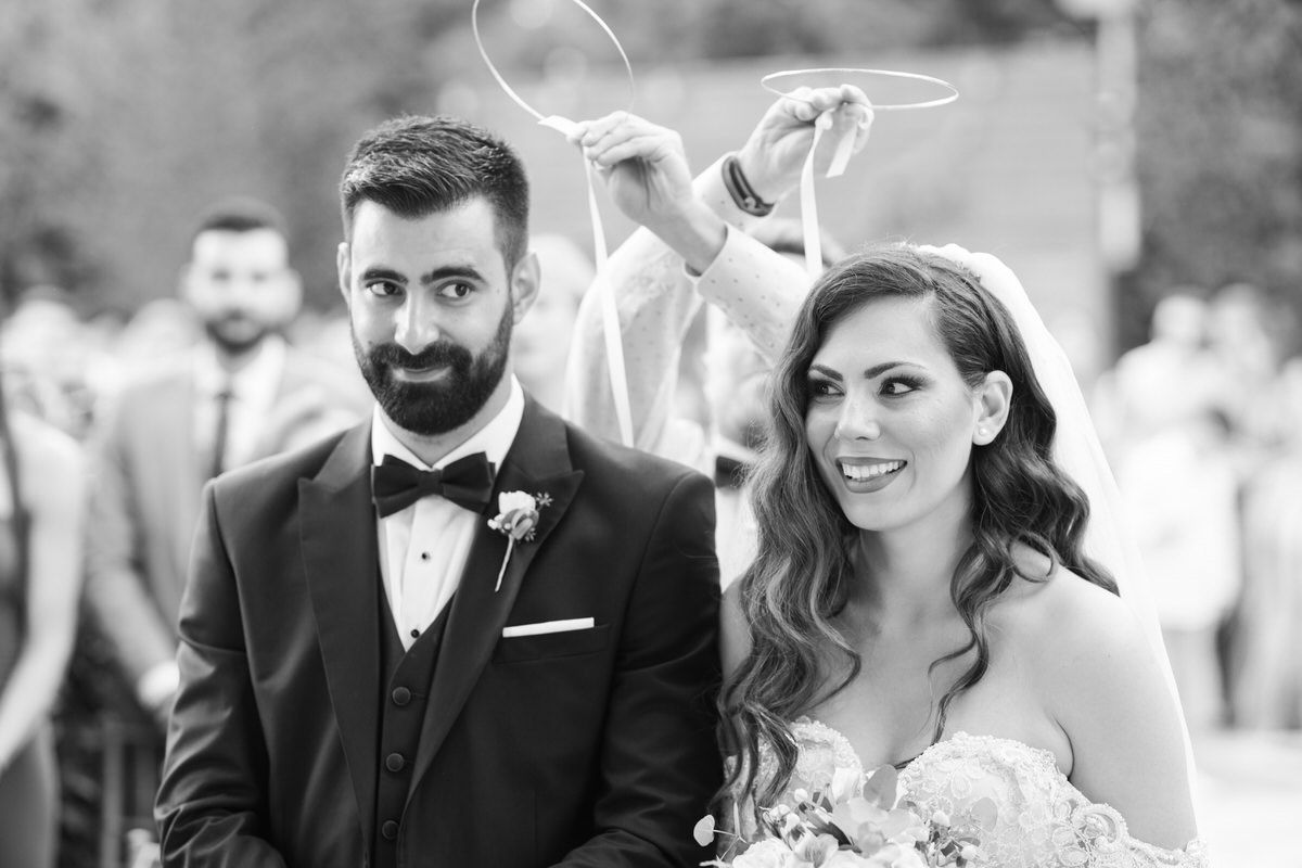 A black and white photograph of a bride and groom smiling together at their outdoor wedding ceremony.
