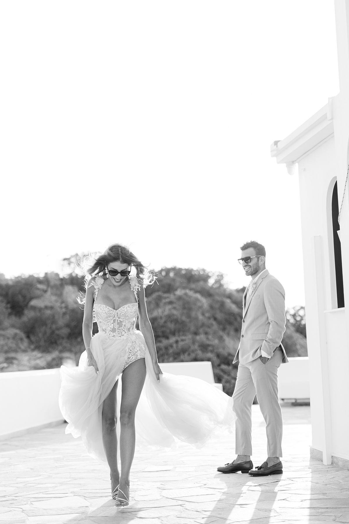 Black-and-white candid of the couple laughing during portraits in Greece