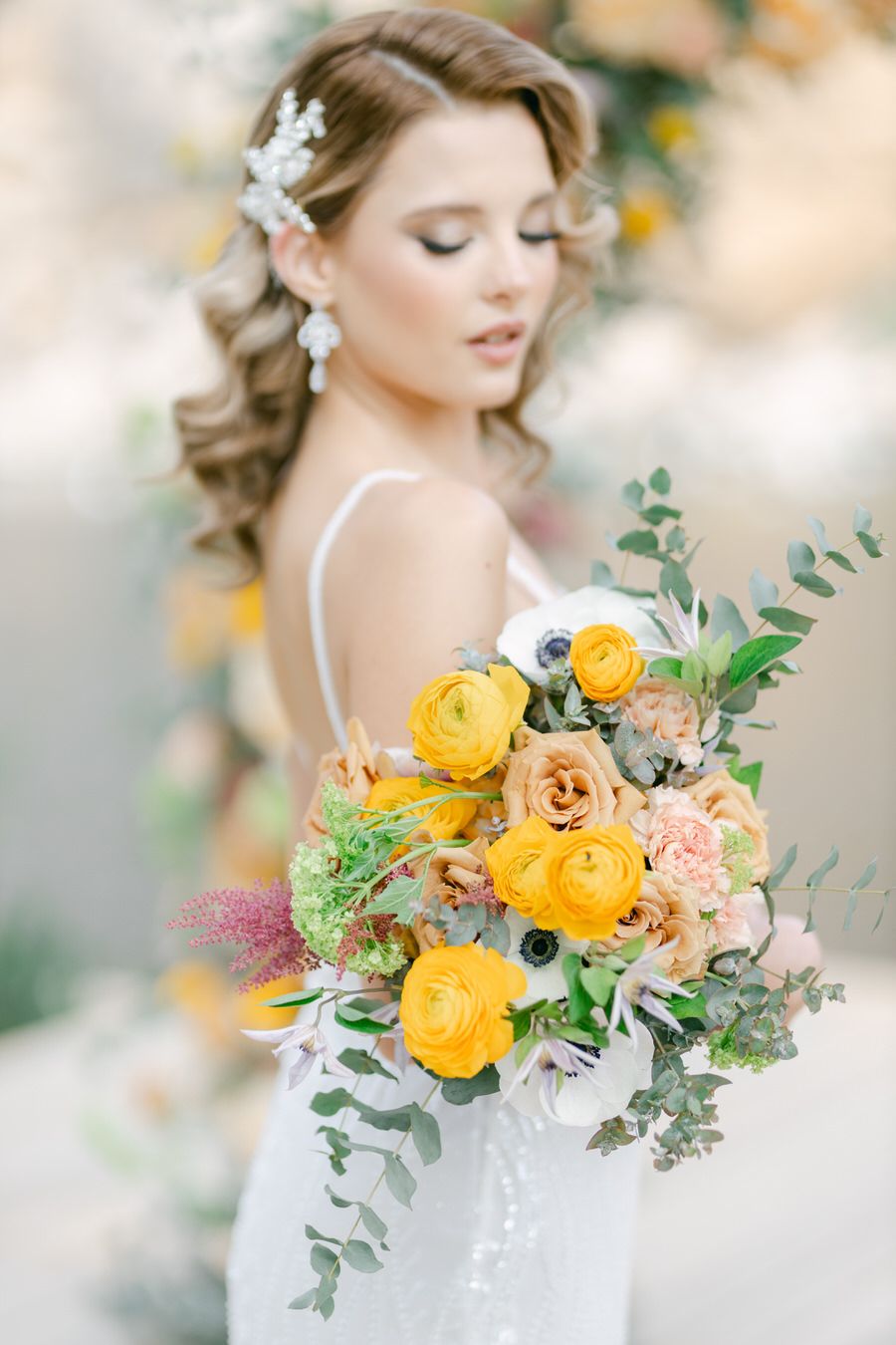 Bridal bouquet featuring yellow ranunculus and peach roses with eucalyptus.