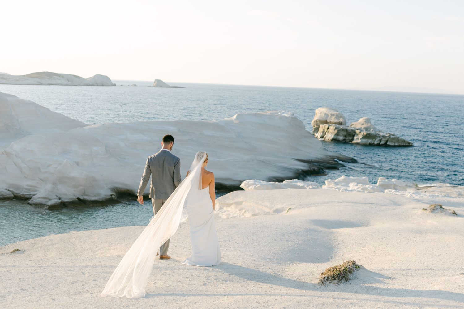 A series of romantic engagement photos with white umbrellas and a flowing red dress against a neutral outdoor backdrop.