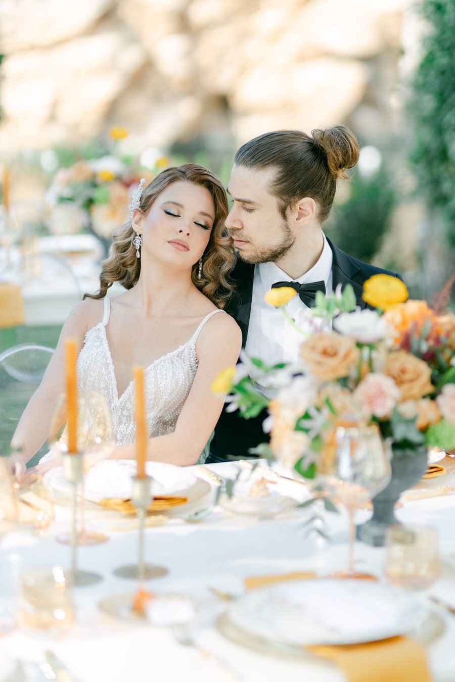 A romantic moment captured at an elegantly set wedding table with candles and floral centerpieces.