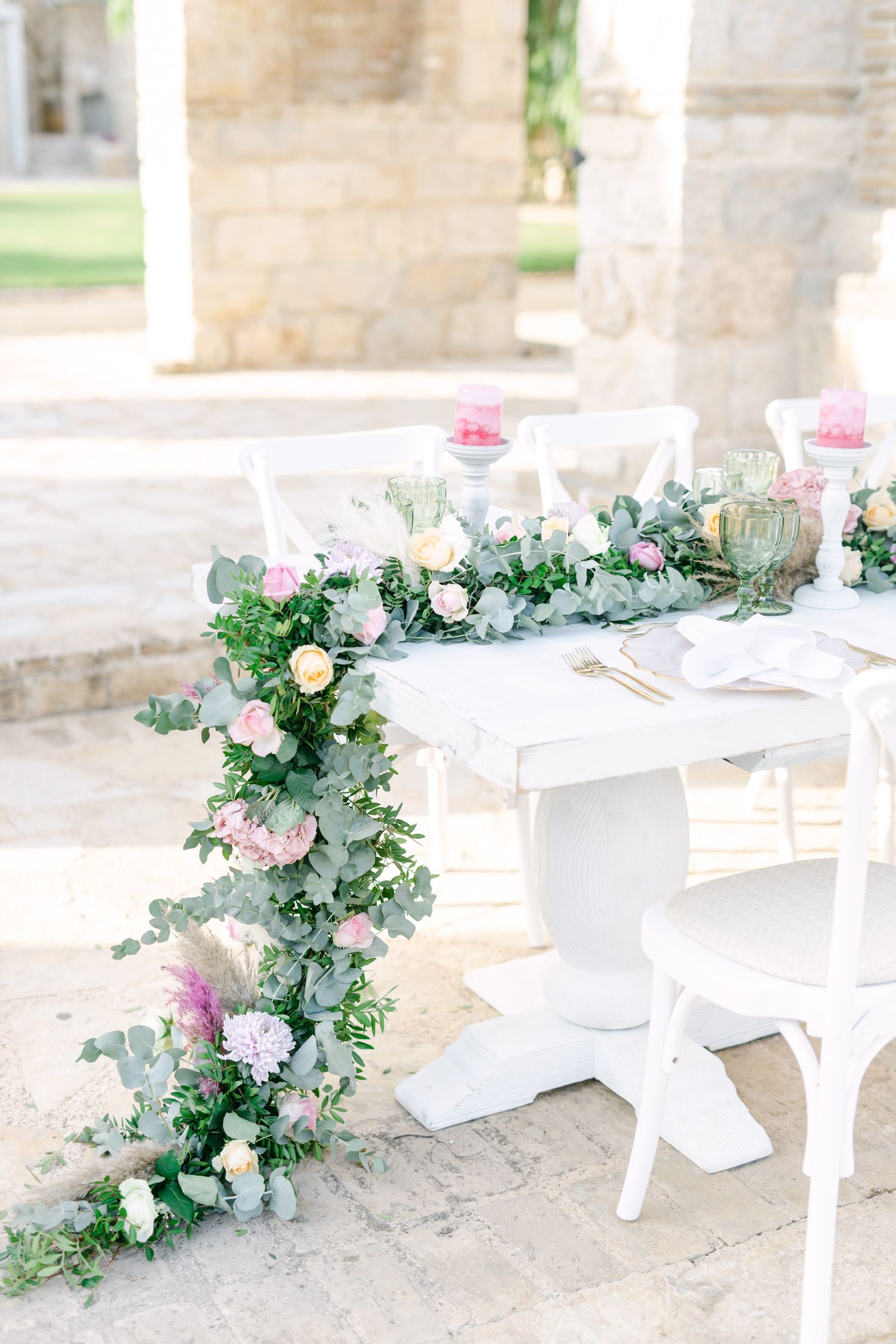 White wedding table decorated with elegant floral runner in pastel pink and green tones.