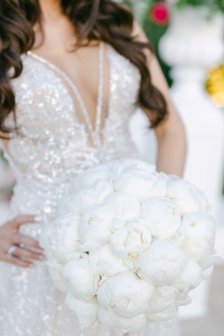 Close-up of sparkly wedding dress and white peony bouquet.